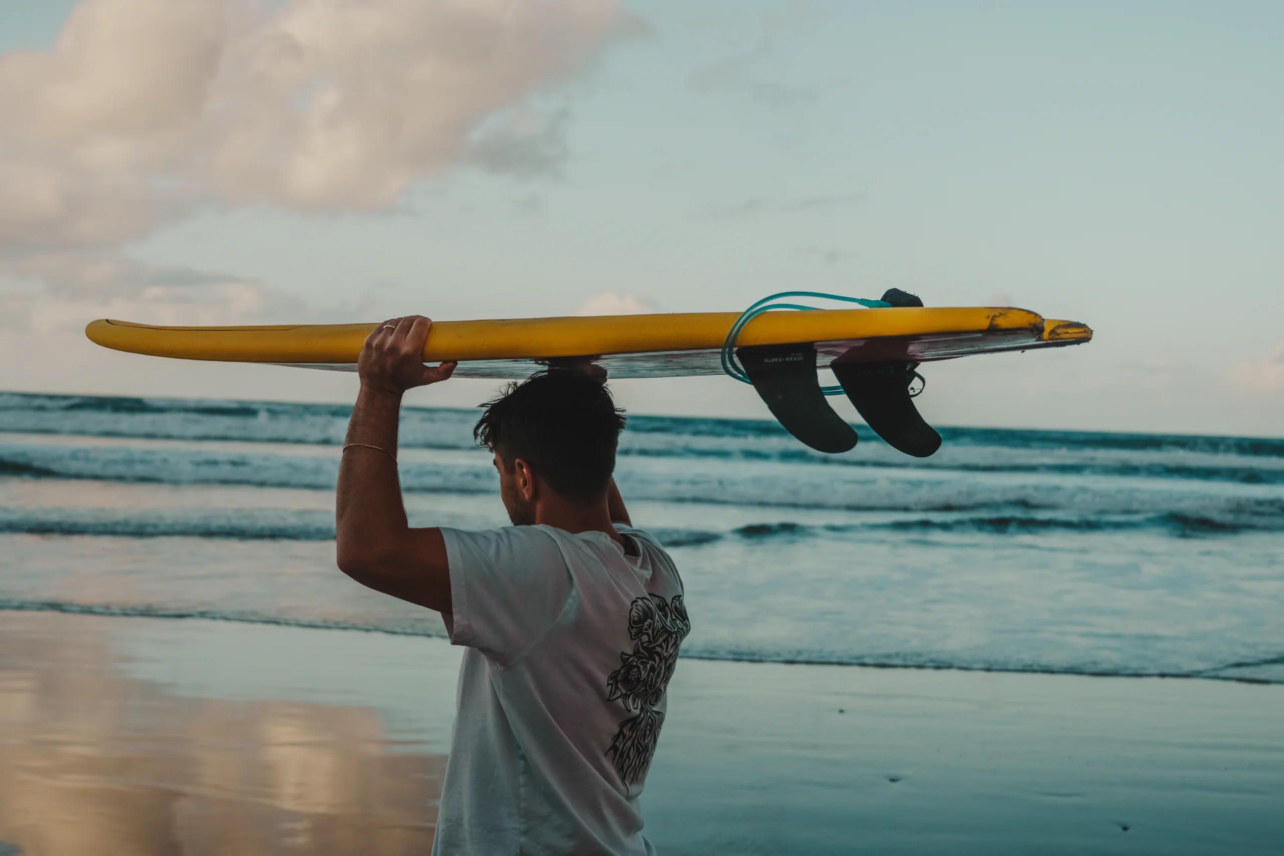 Ieser holding a board above his head in Famara beach
