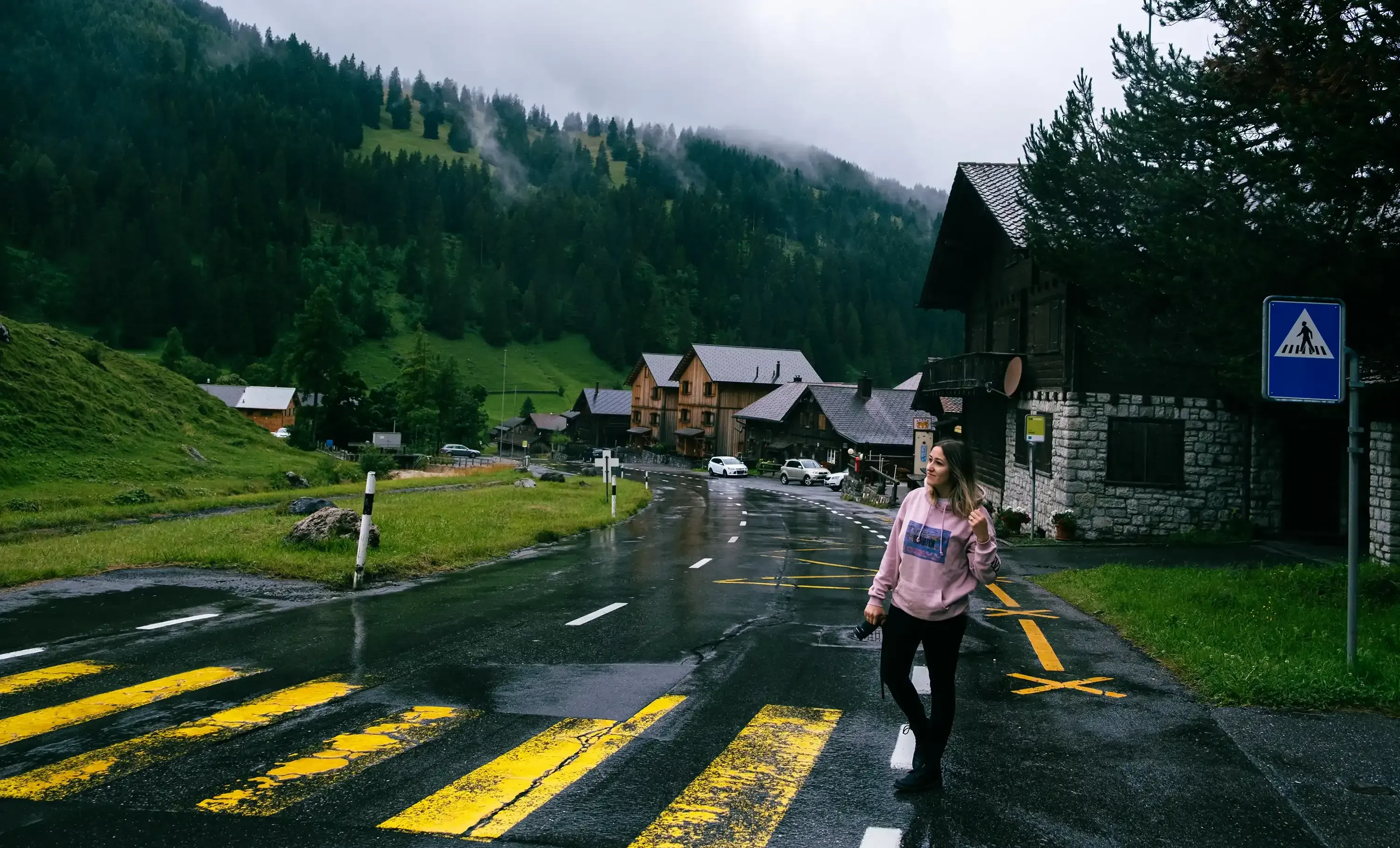 Letizia walking on a path surrounded by traditional wooden alpine huts (Baite).
