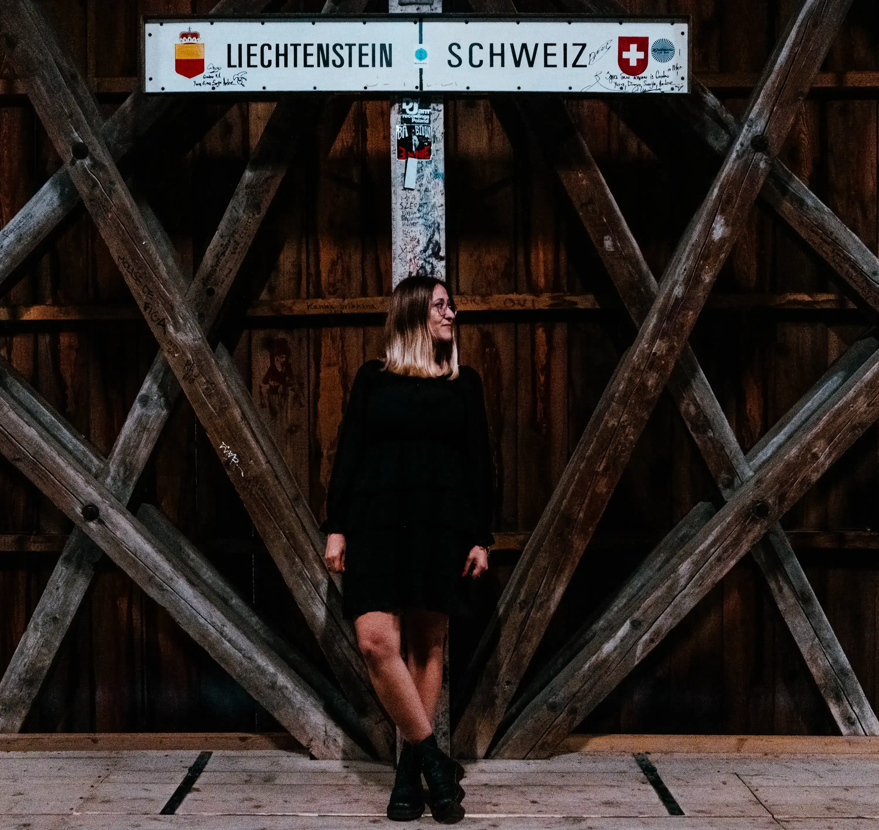 Letizia standing next to the border sign marker on the Old Rhine Bridge between Liechtenstein and Switzerland