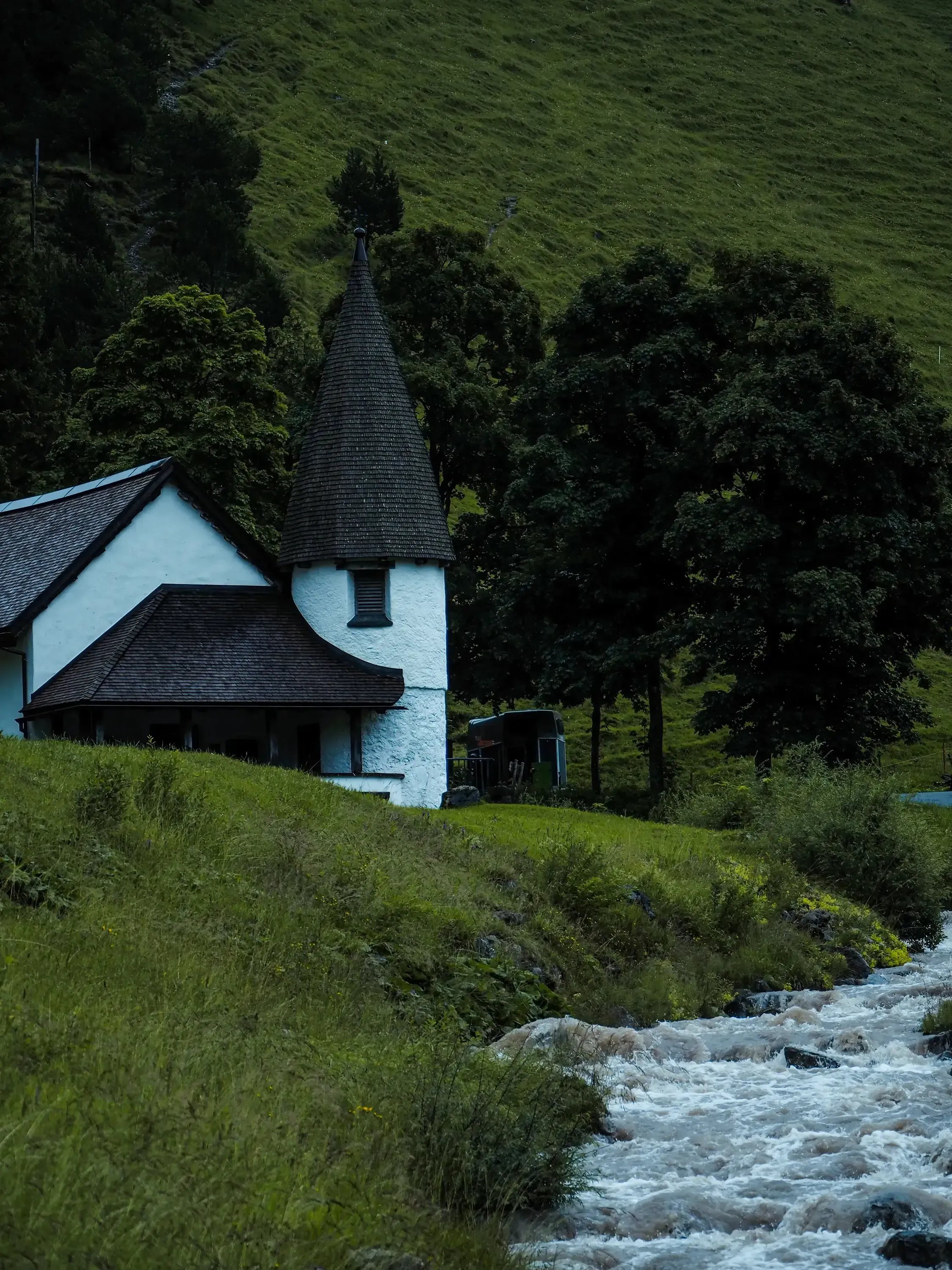 White church with a spire situated close to the banks of a flowing river.