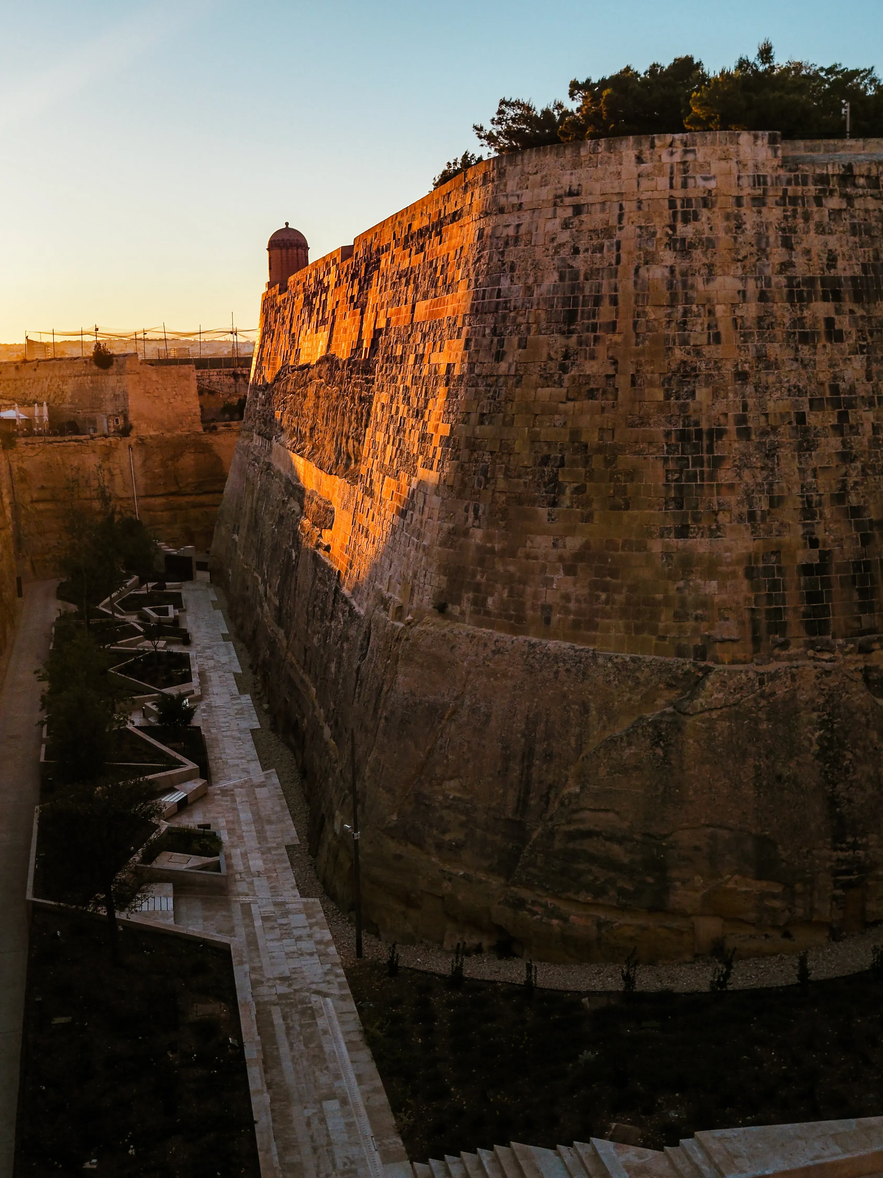 Exterior view of the tall, imposing stone defense walls surrounding the city of Mdina.