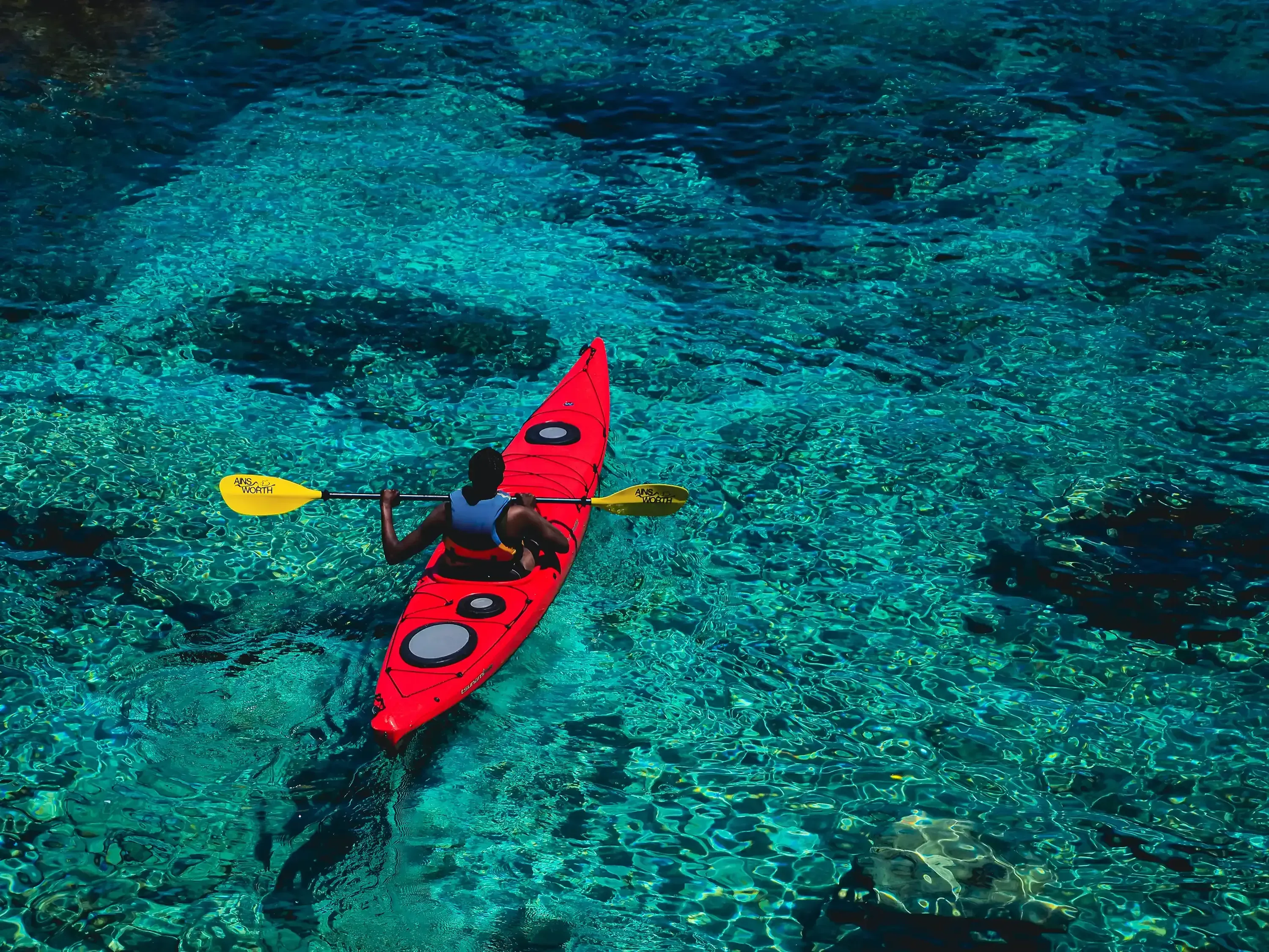 A small canoe floating on the clear, calm waters of the Maltese coast.