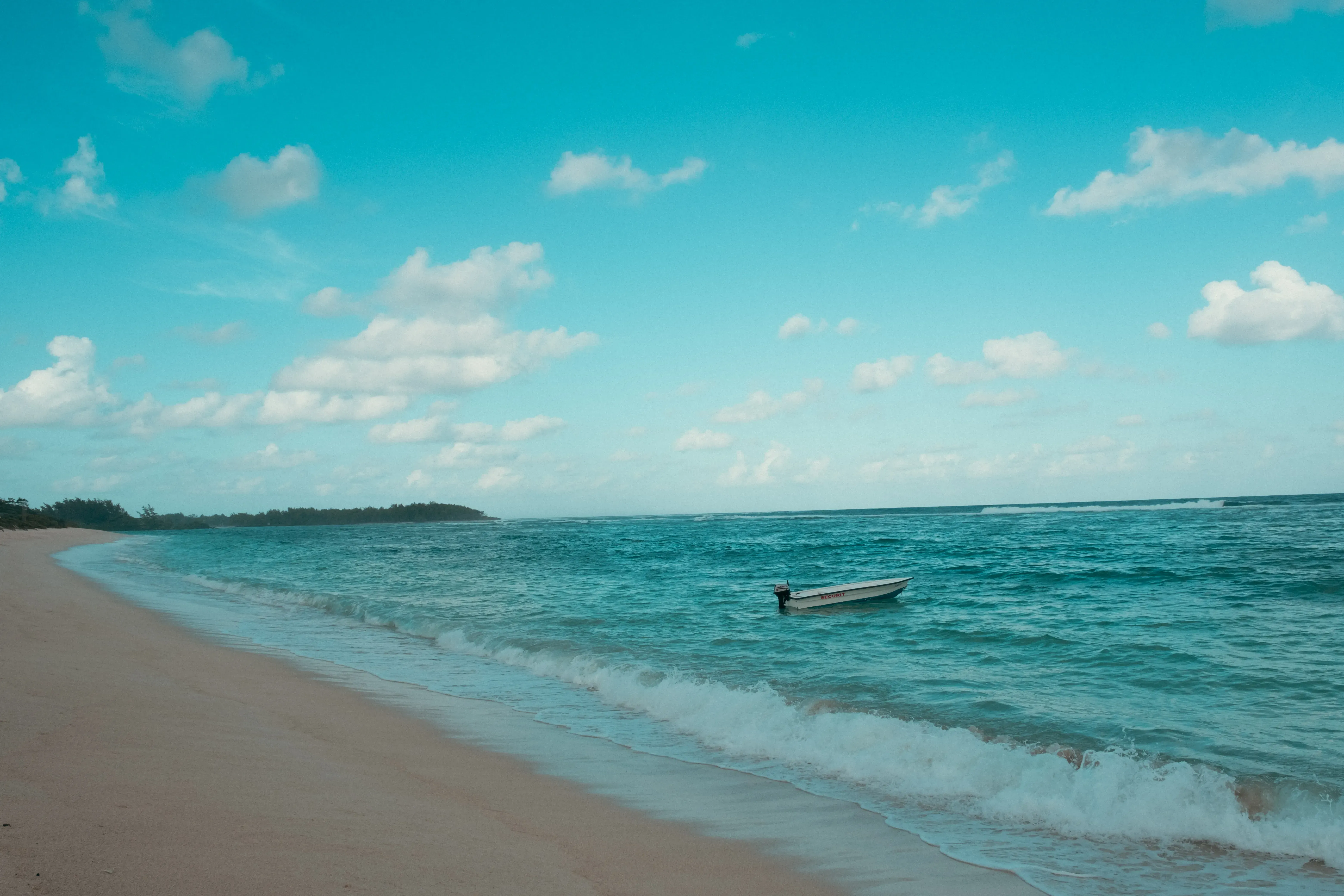 A small fishing boat or speed boat resting on the sand of La Cambuse beach.