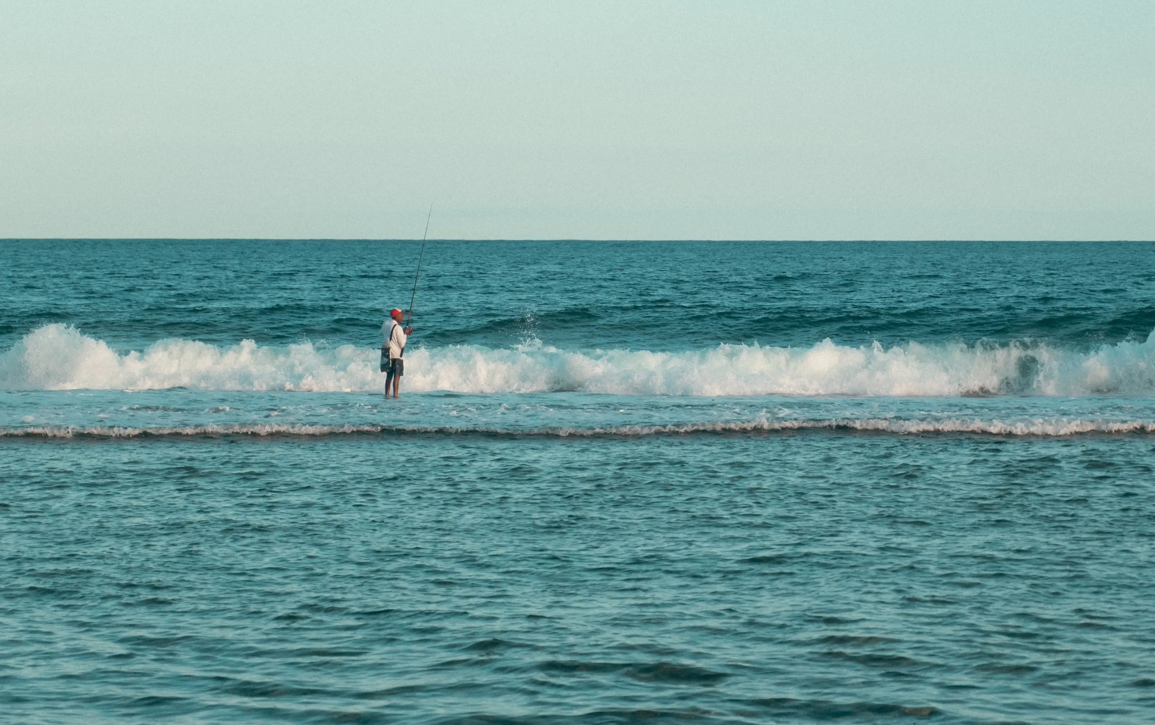 A local fisherman standing on the beach in Mauritius, preparing casting a line into the ocean.