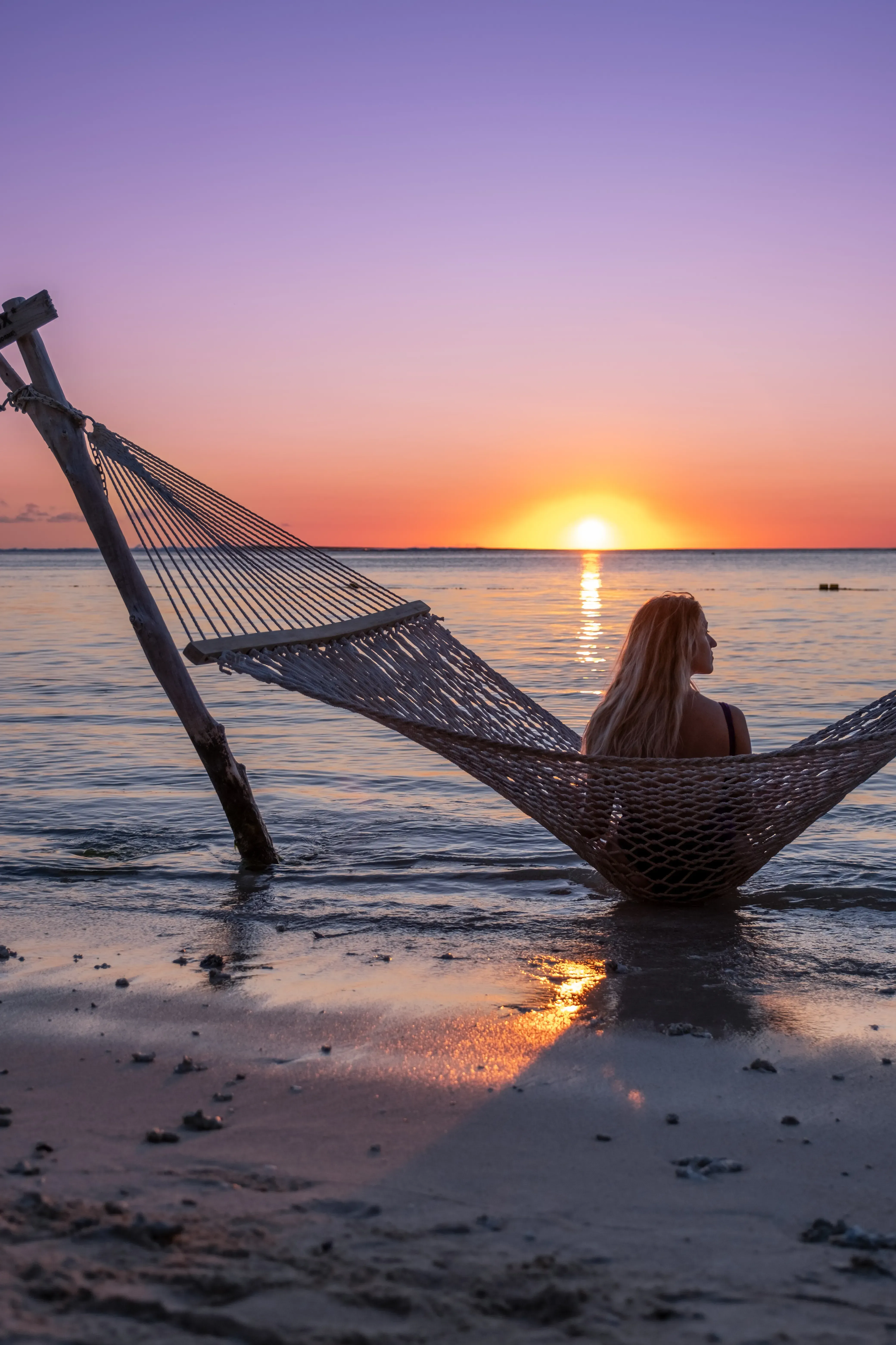Letizia sitting comfortably in a hammock strung between palm trees on Le Morne beach.