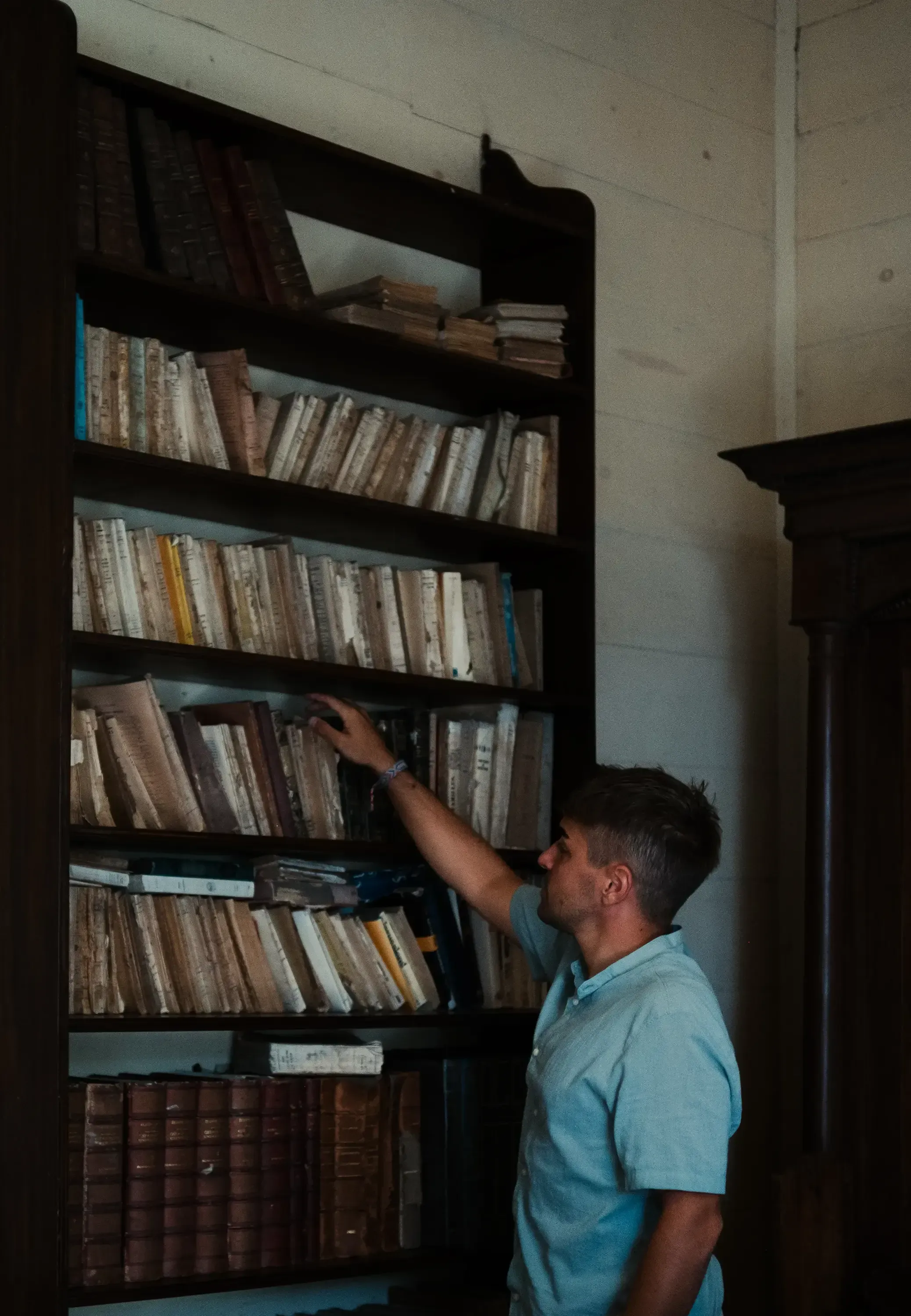 Person browsing or examining books within the library or study of a preserved historic colonial house in Mauritius.