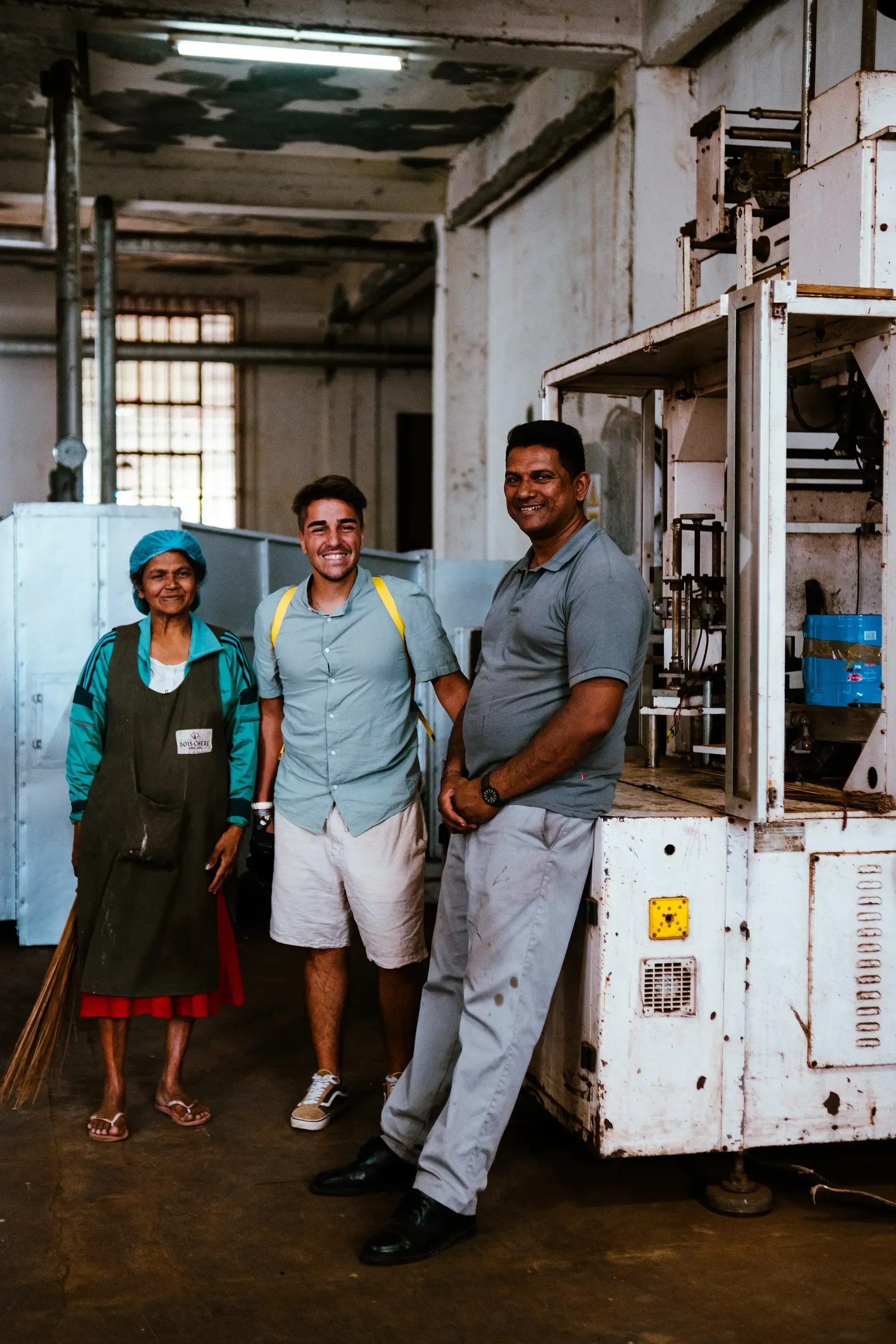 eser standing and posing with two employees inside the tea factory of Bois Cheri 
