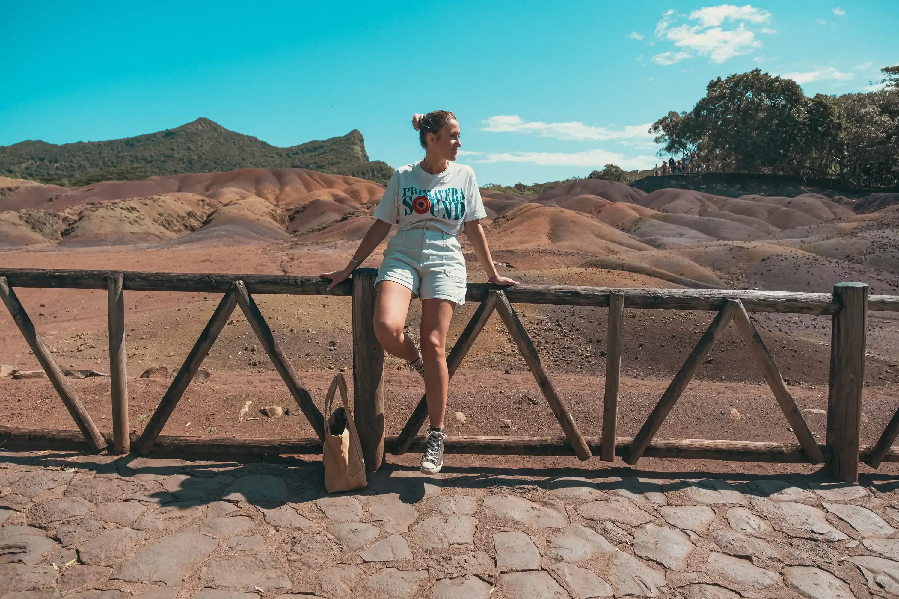 Letizia sitting on the wooden fence or railing, posing with the natural landscape in the background.