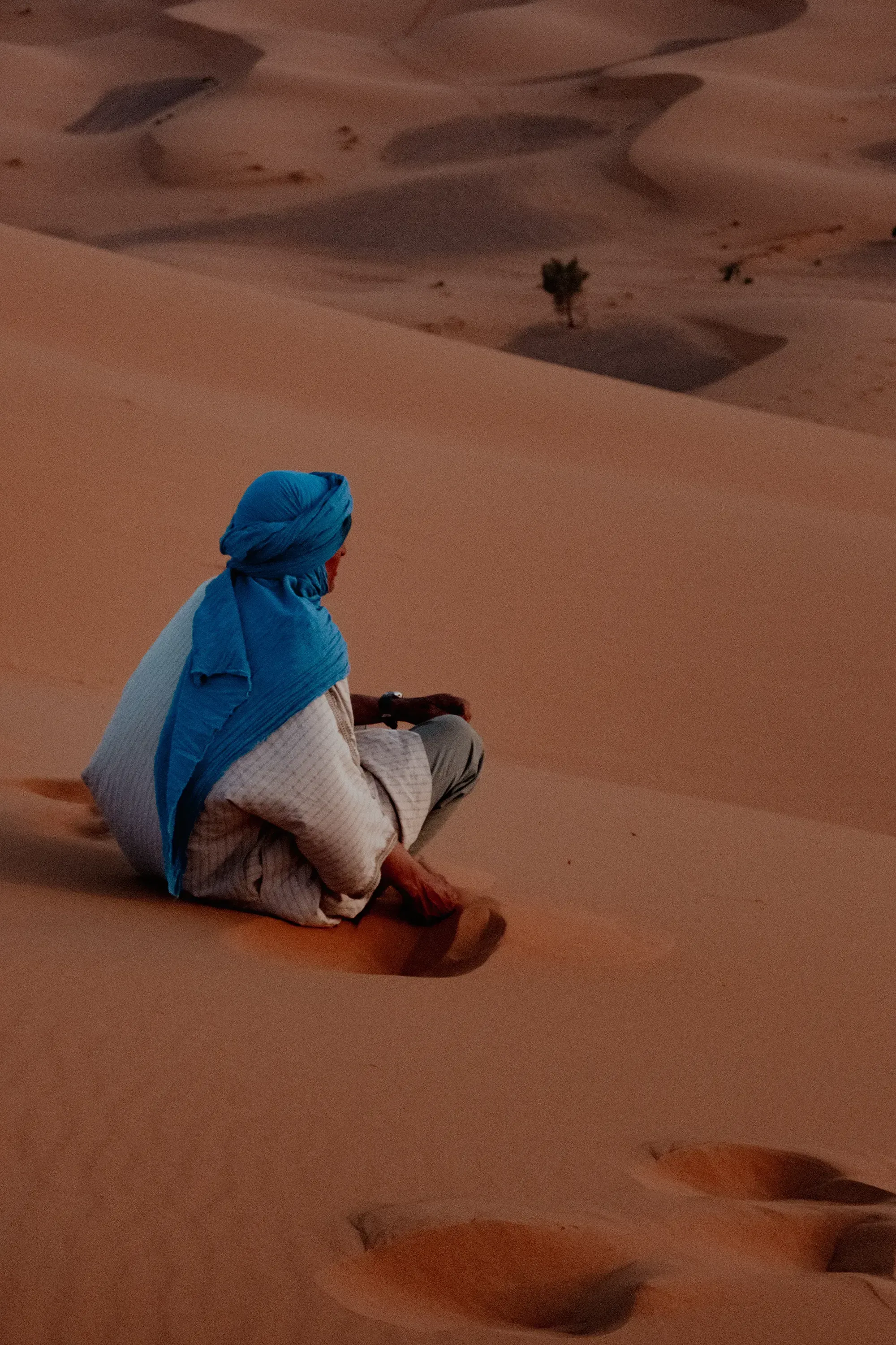 Desert man gently moving the fine orange sand with his hand.