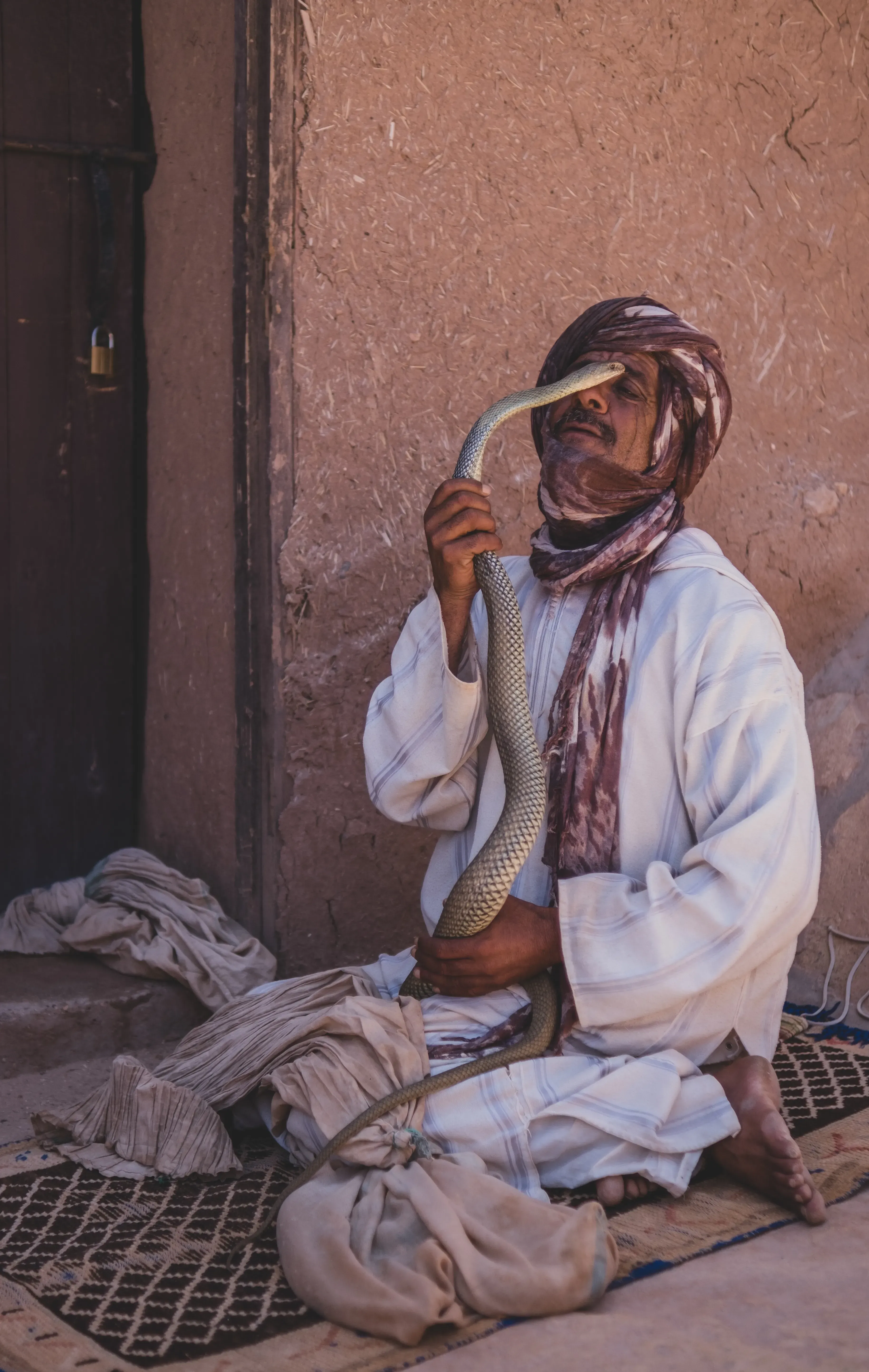 Street performer (snake charmer) playing a wind instrument to a cobra in the Jemaa el-Fna square.