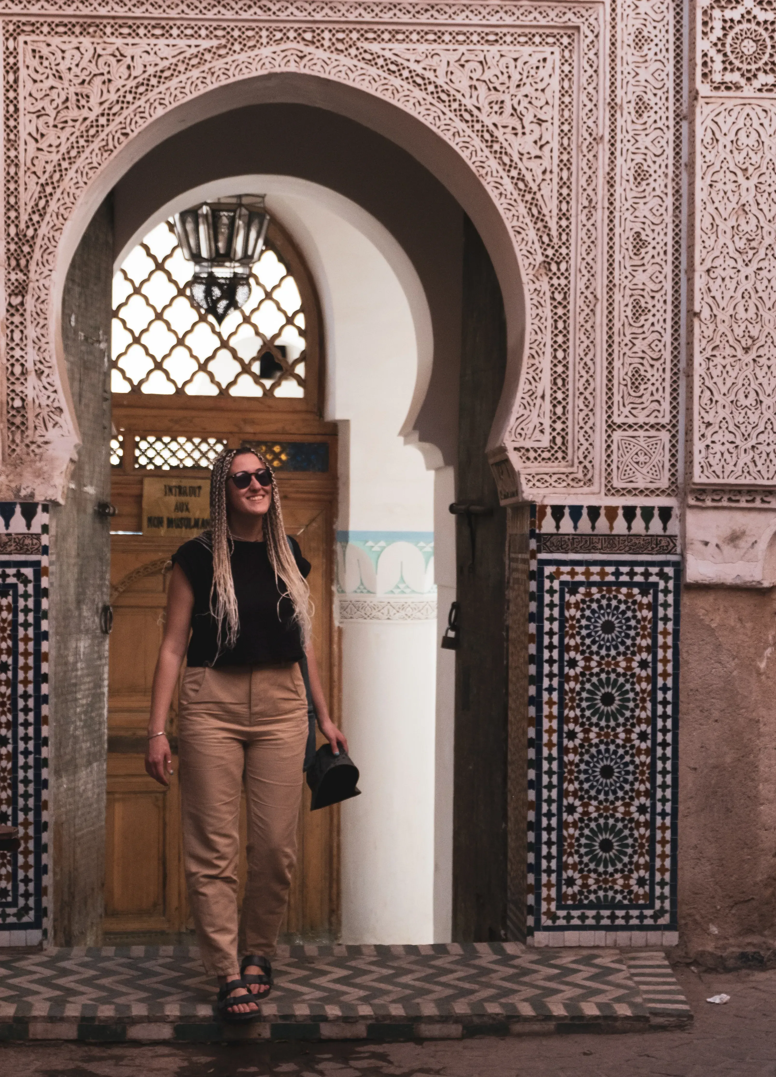 Letizia stepping out of a traditional, ornate wooden doorway.