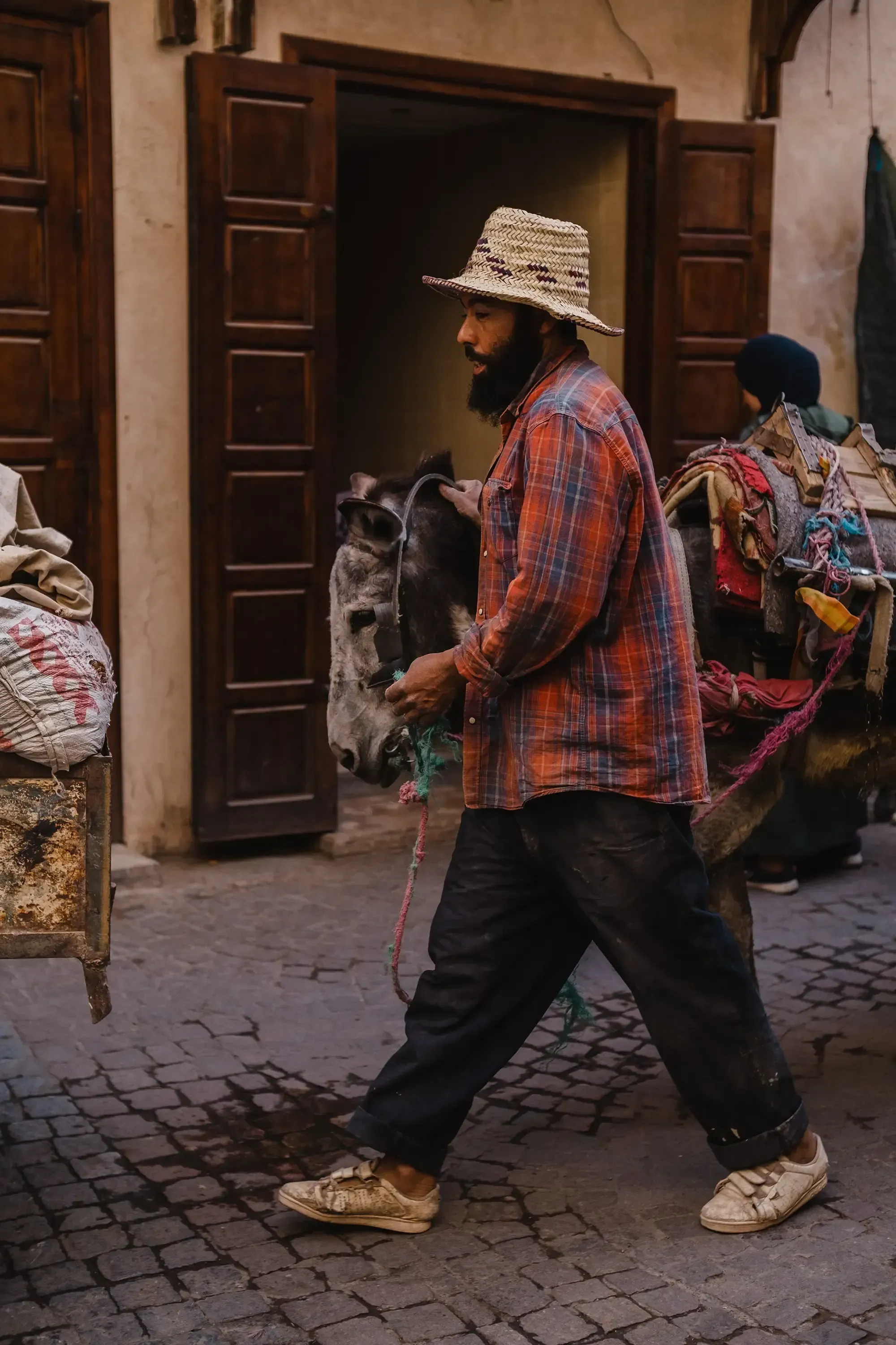 A local man pushing or pulling a donkey through the crowded street.