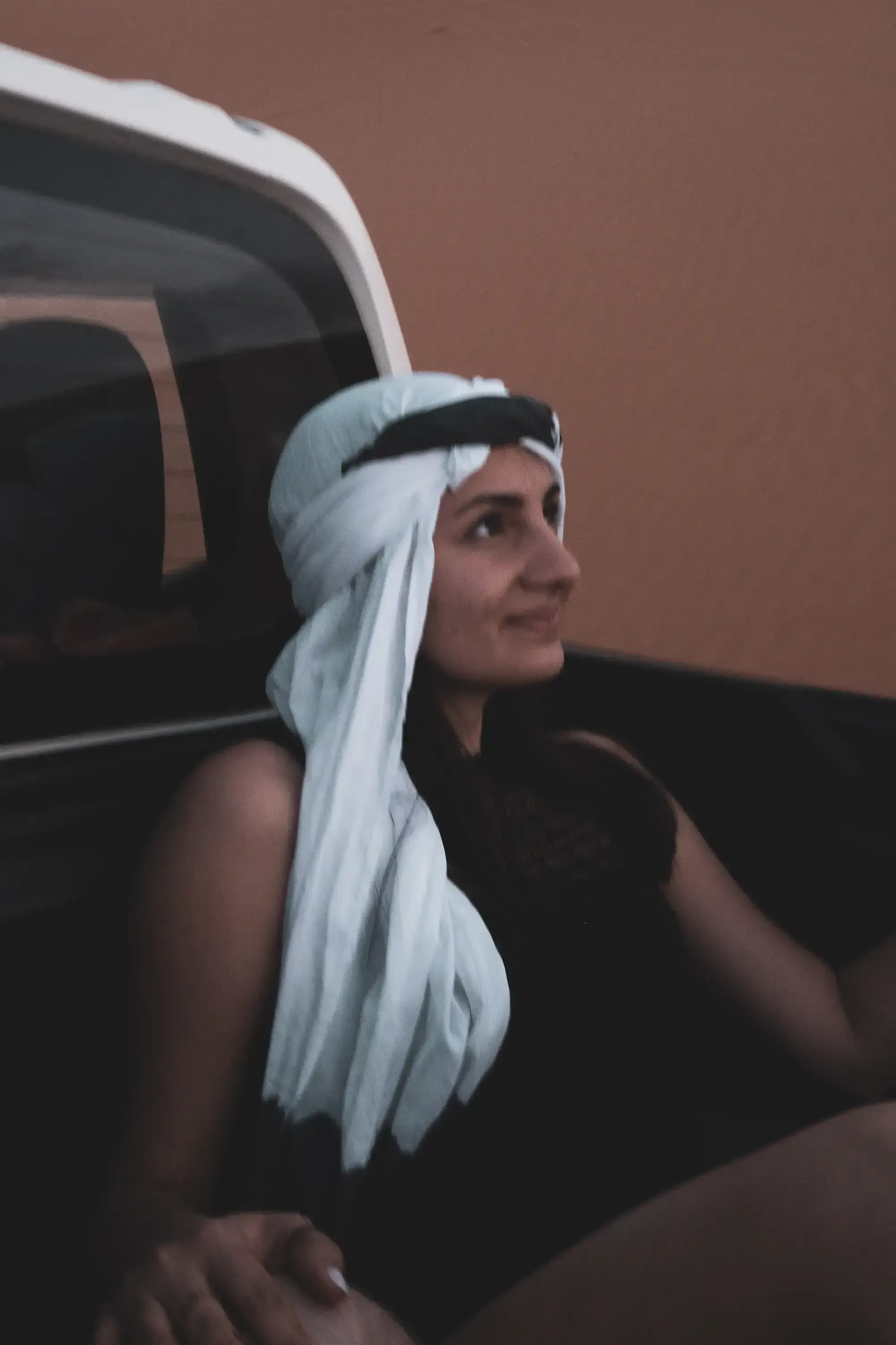 Feride sitting on the flatbed of a transportation truck in the desert camp.