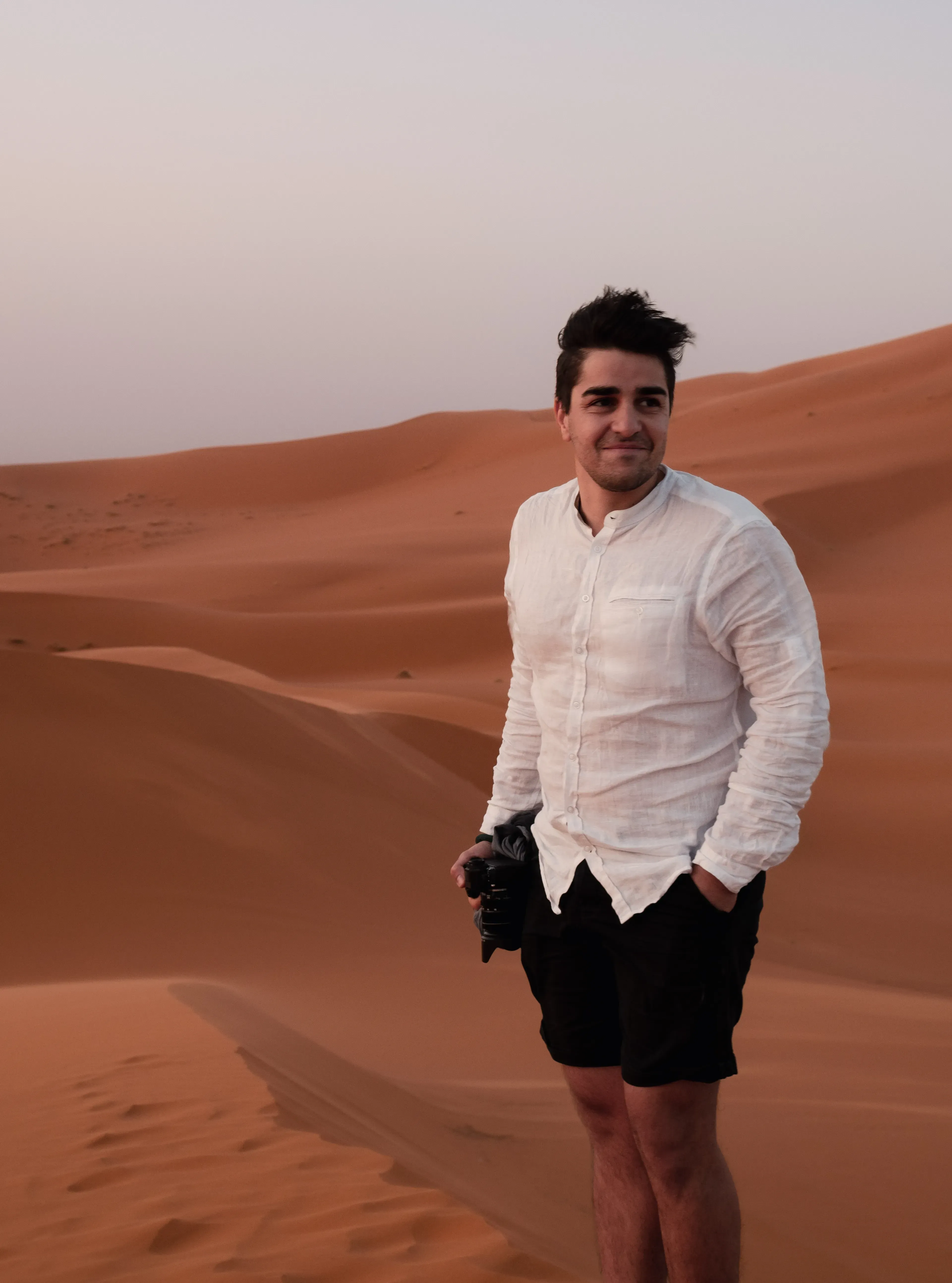 Ieser standing on a dune with hair blowing dramatically in the desert wind.