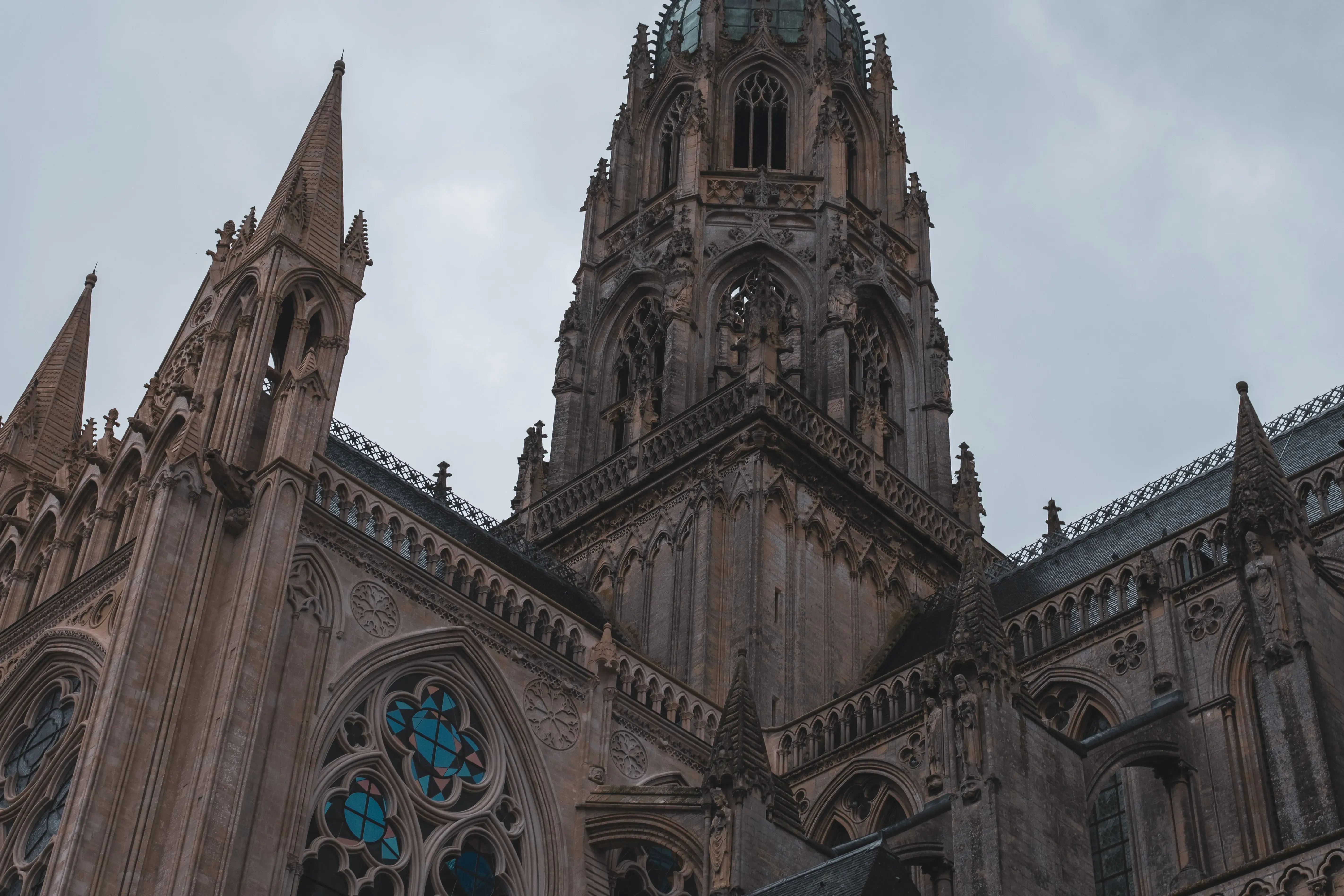 A view looking up at the towering spire or bell tower of Bayeux Cathedral from its base.