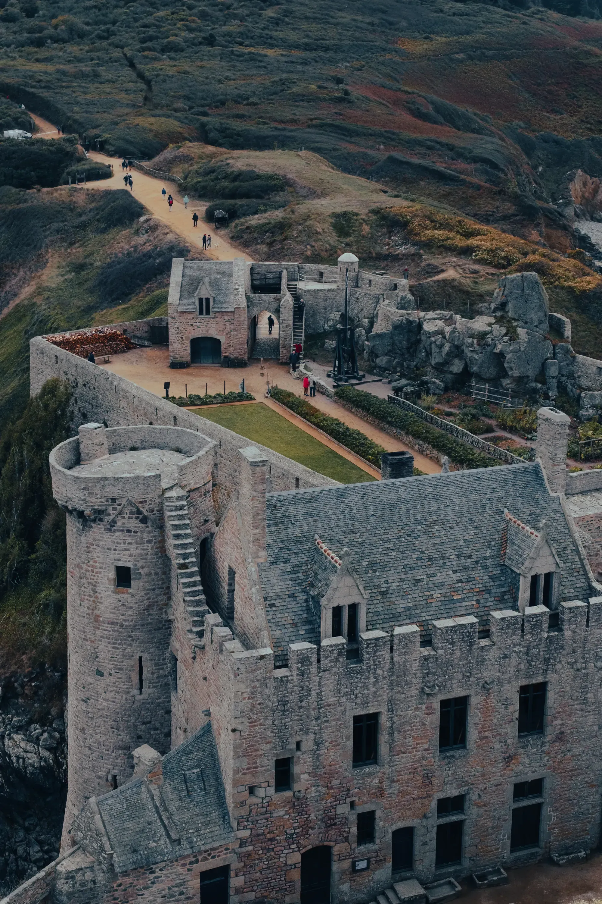 A high-angle view from the main tower of Fort La Latte, looking down over the courtyard and the sea below.
