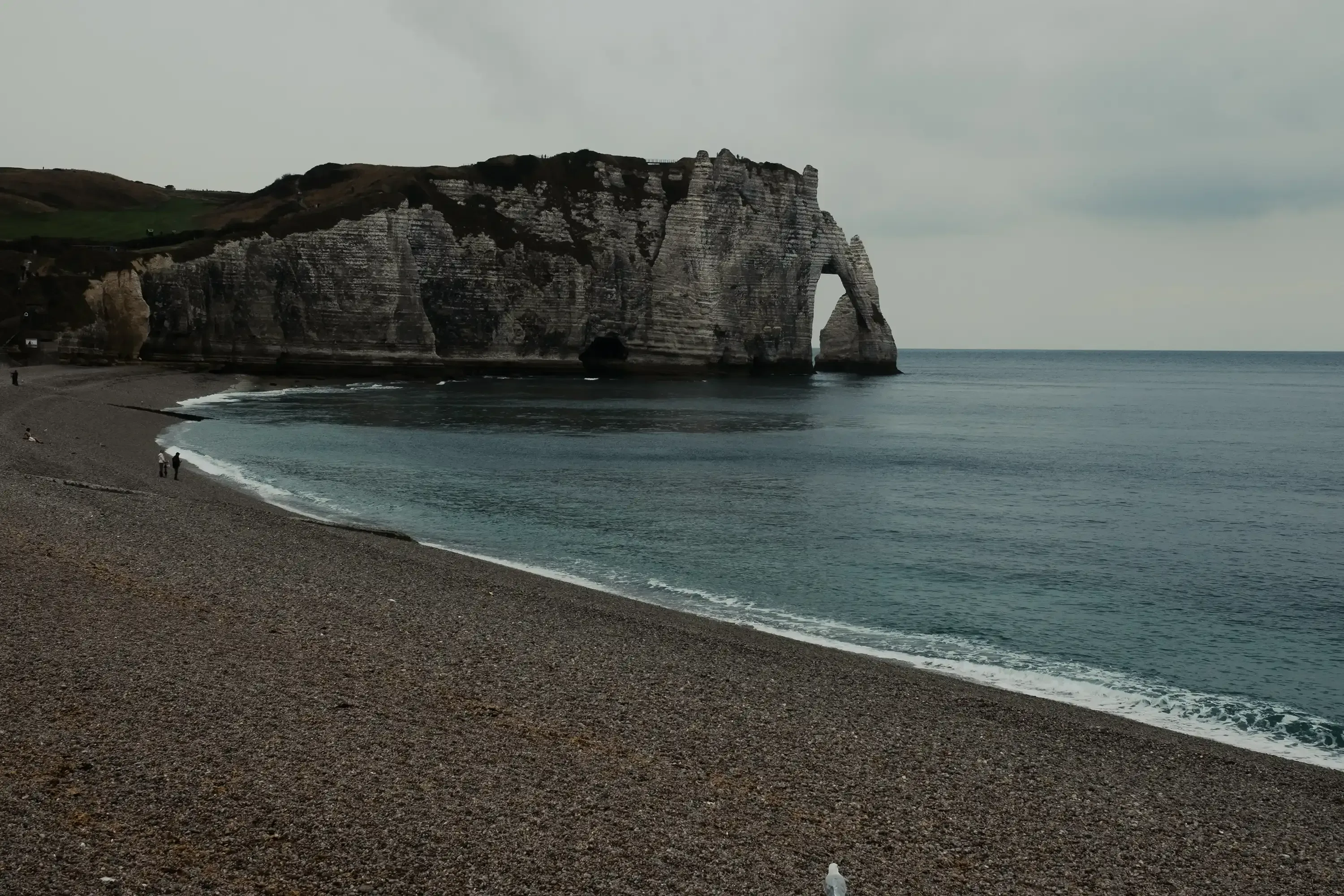 The pebble beach of Étretat looking out toward the English Channel and the cliff formations.
