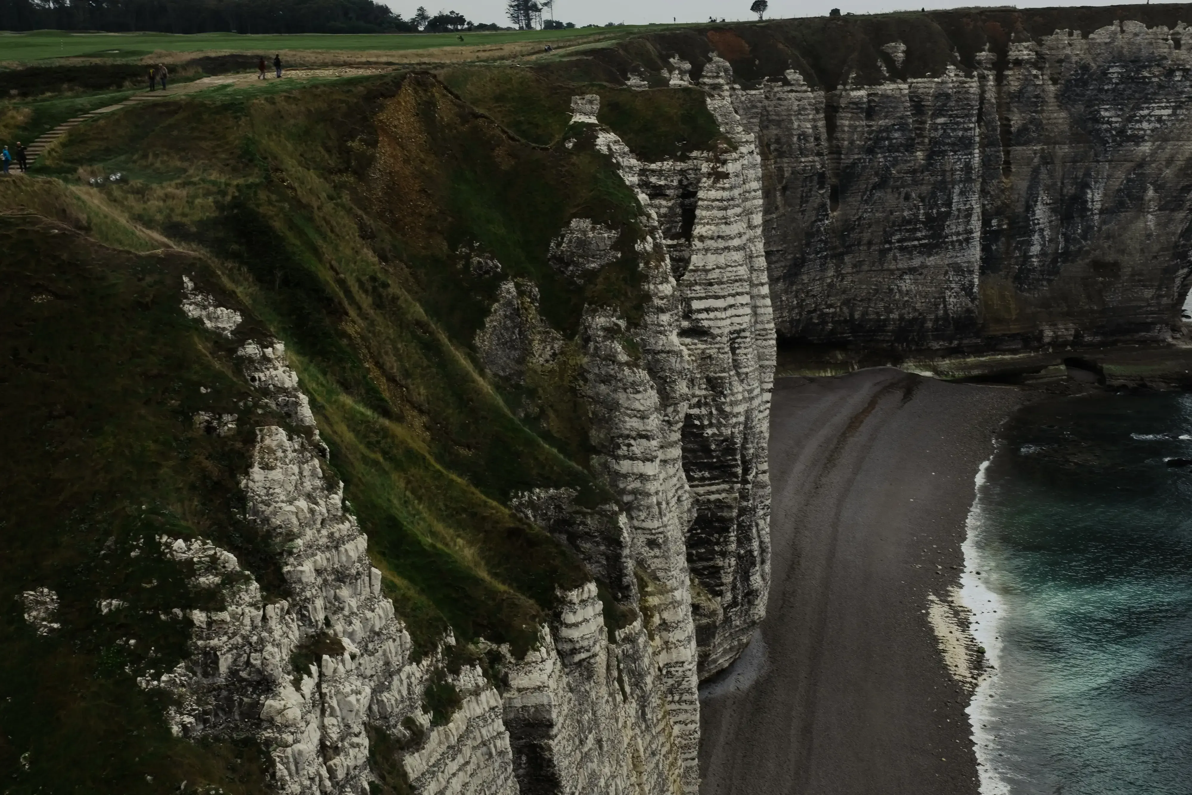 A high-angle, panoramic view of the iconic white cliffs (falaises) and the natural arches of Étretat.