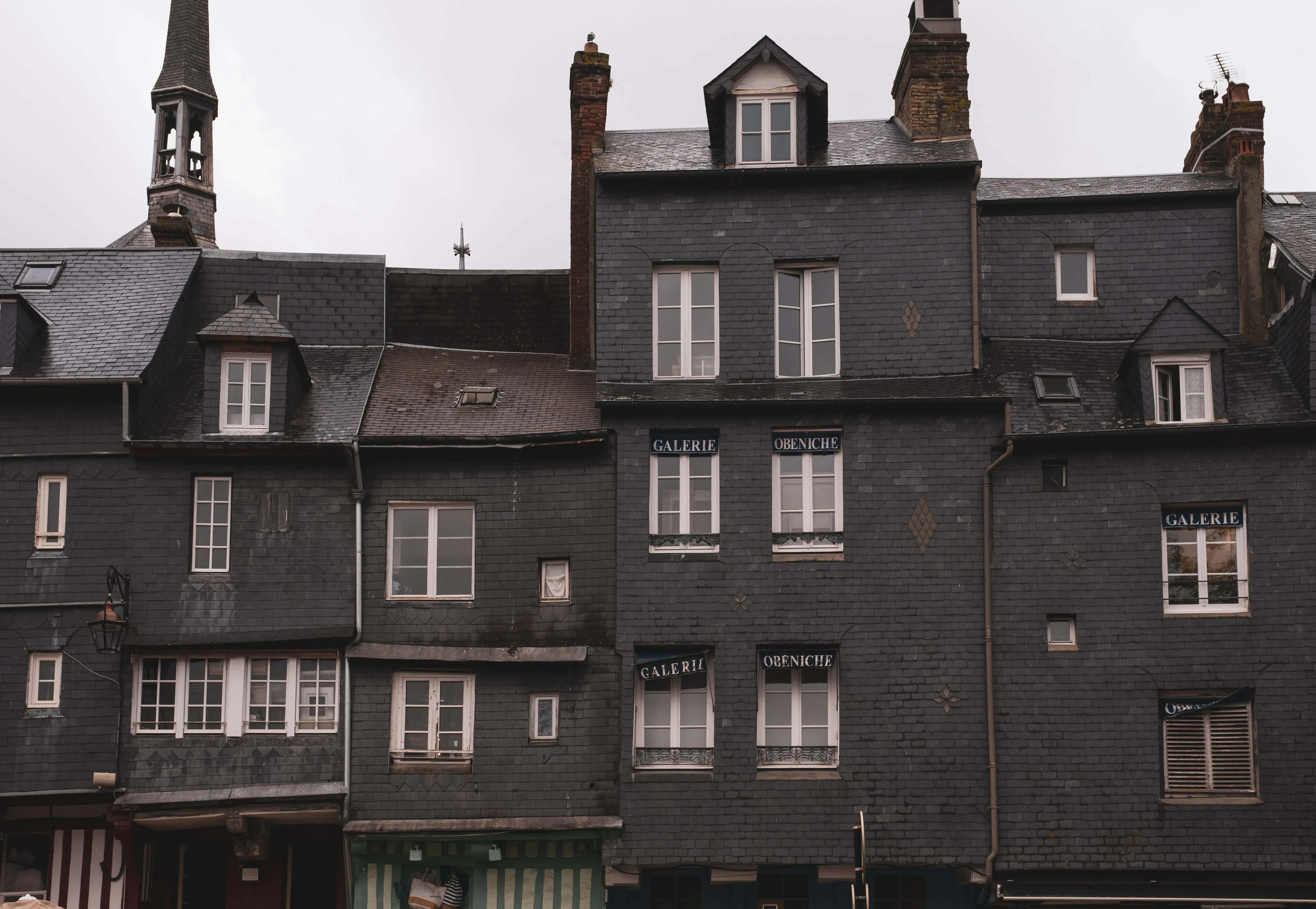The characteristic tall, brown, and narrow half-timbered houses lining the harbor (Vieux Bassin) of Honfleur.