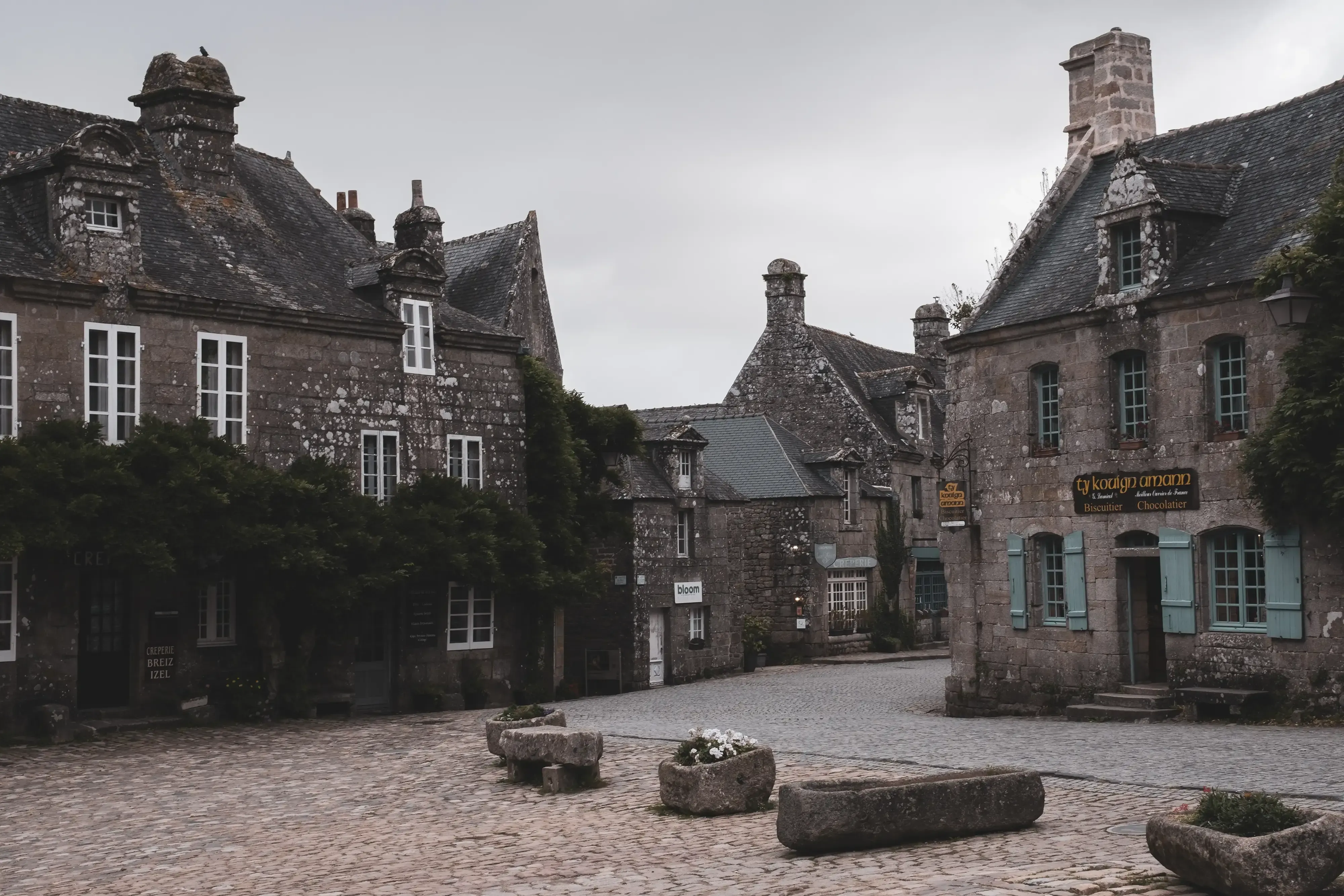 The main square of Locronan, featuring a central stone well and historic buildings.