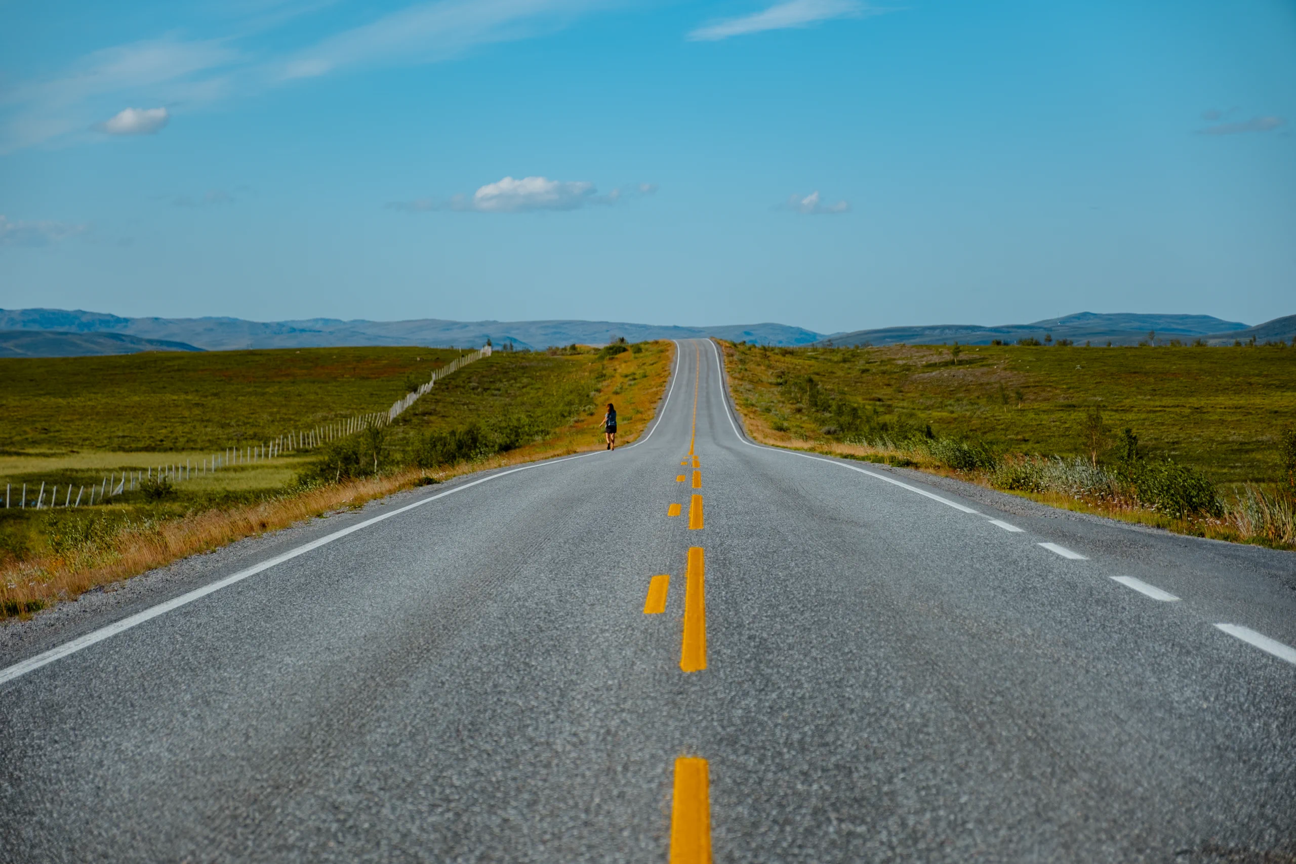 Long, straight road stretching through the remote Swedish landscape.