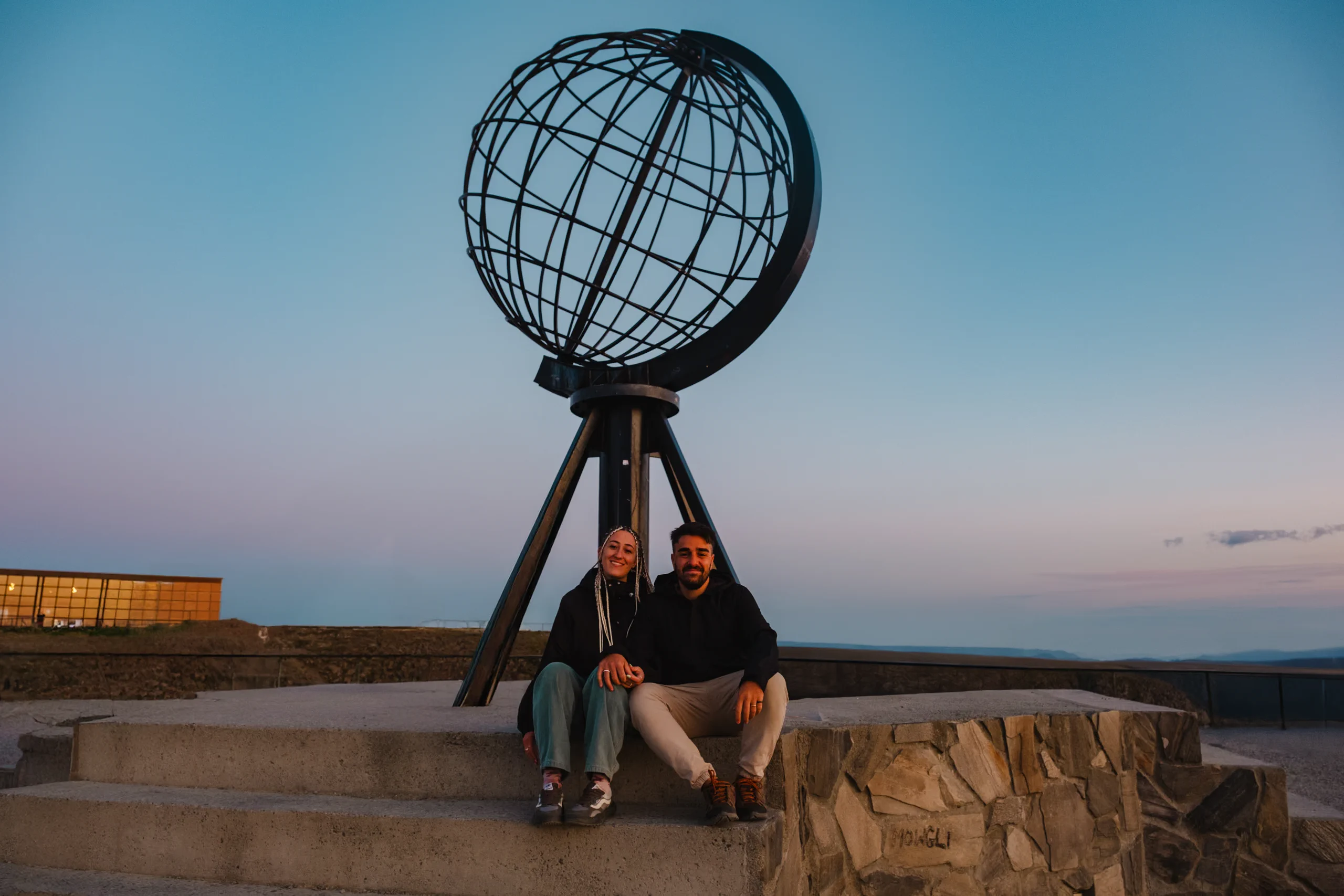 Person and Letizia sitting in front of the famous globe at North Cape