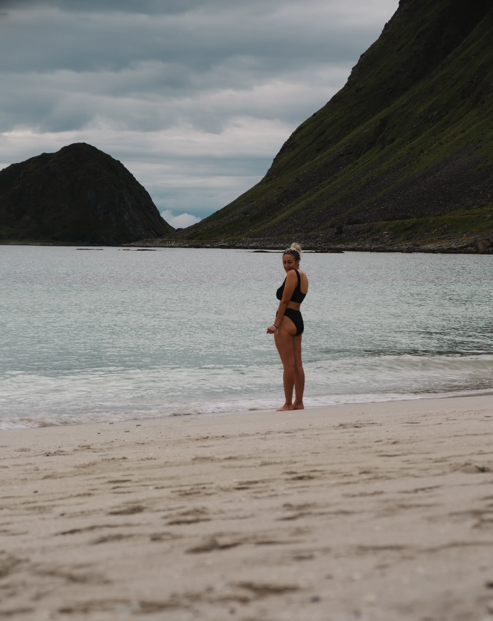 Letizia walking on a white sand beach with turquoise water in Arctic Norway.