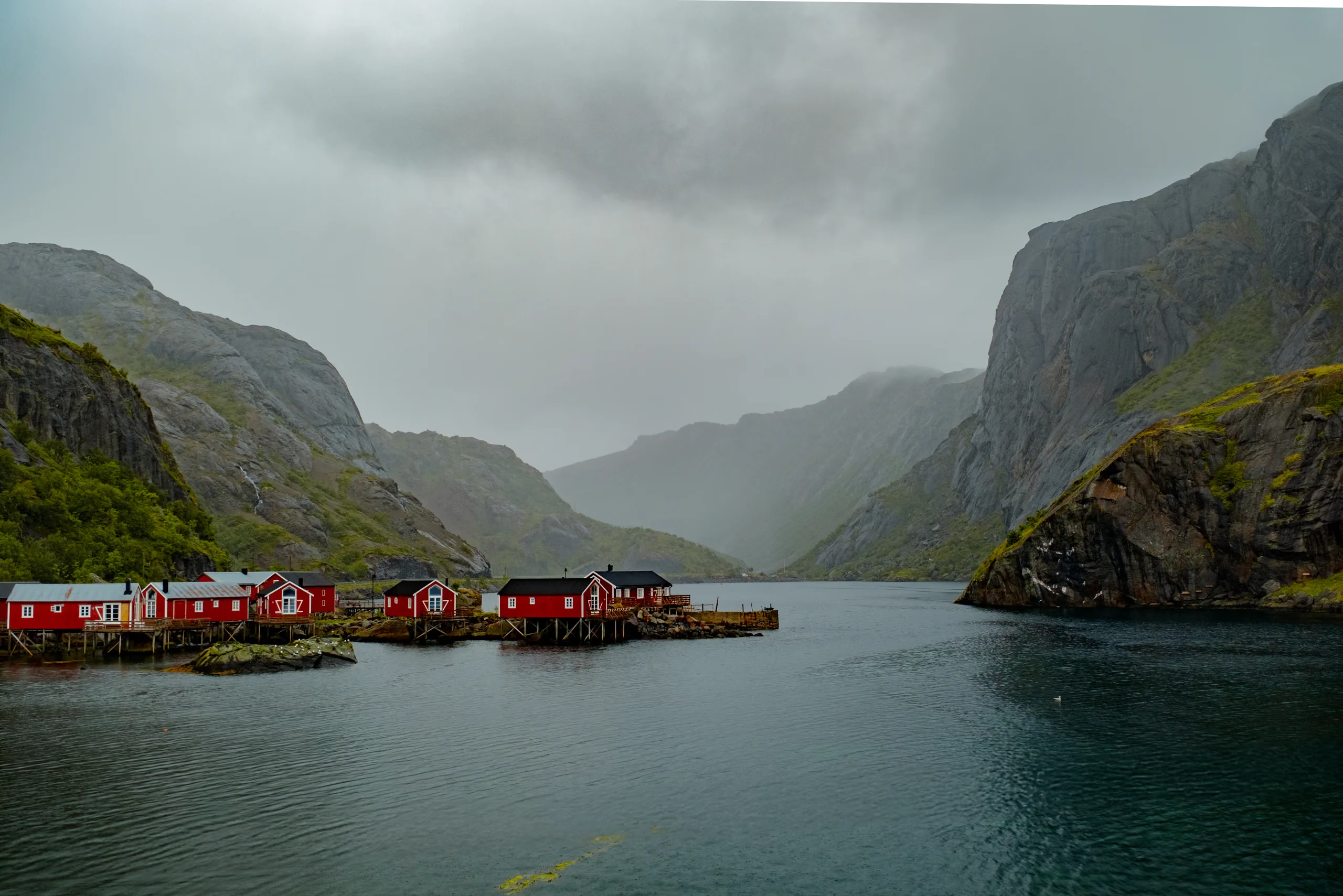 Distant view of the traditional red fishing huts (rorbuer) scattered along the Lofoten coastline.