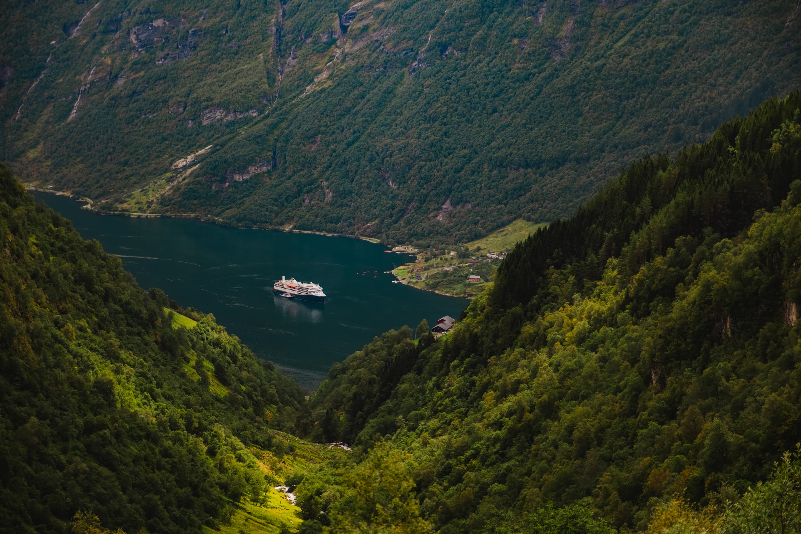Ferry boat navigating the calm, turquoise waters of the Geirangerfjord.