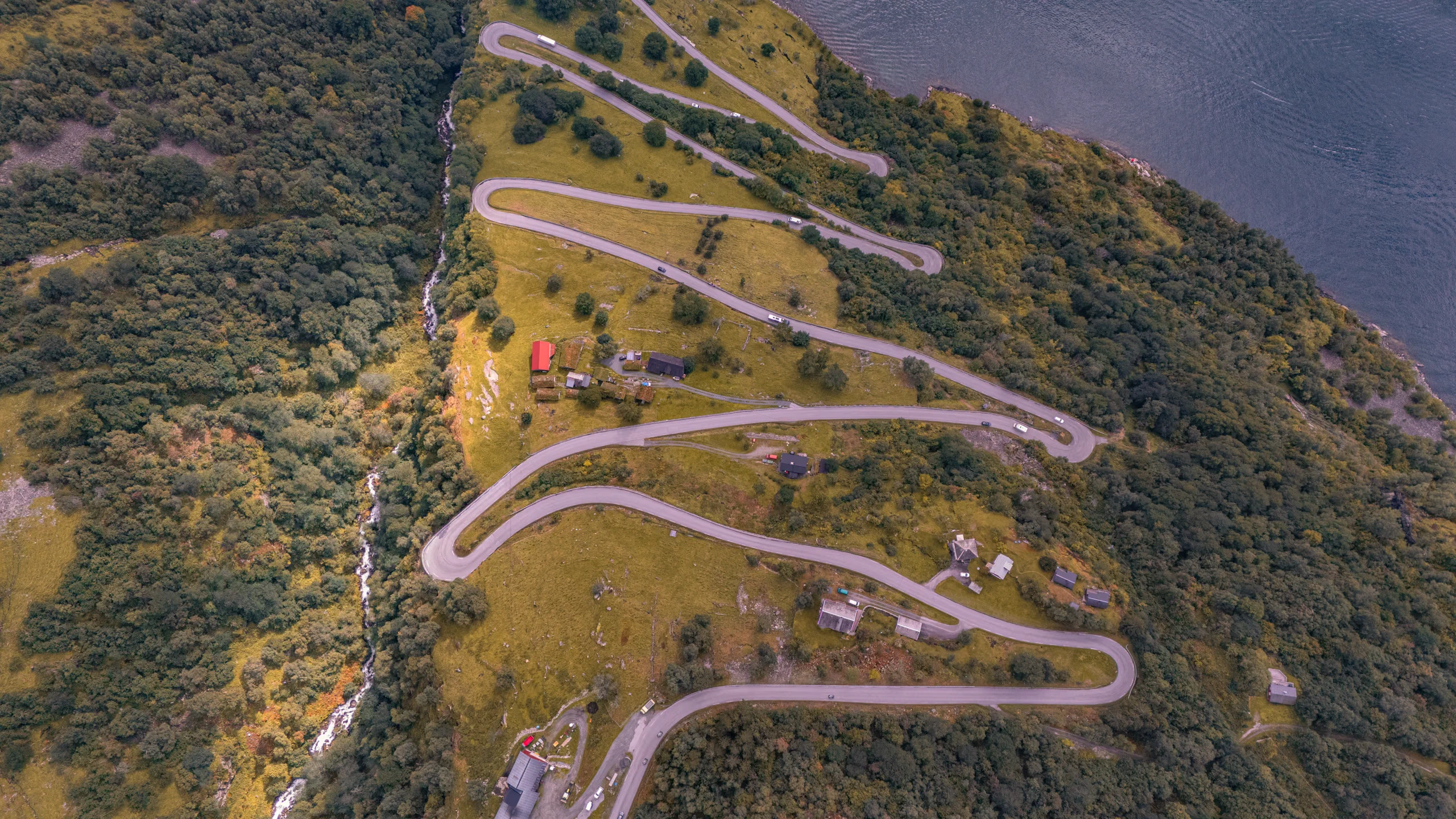 Serpentine mountain road with sharp turns winding down towards the fjord.