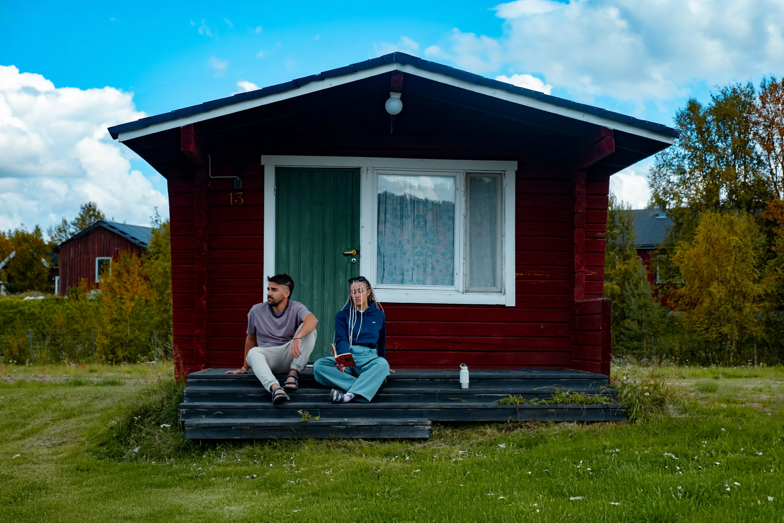 Ieser and Letizia sitting in front of a quaint red wooden house in Sweden.