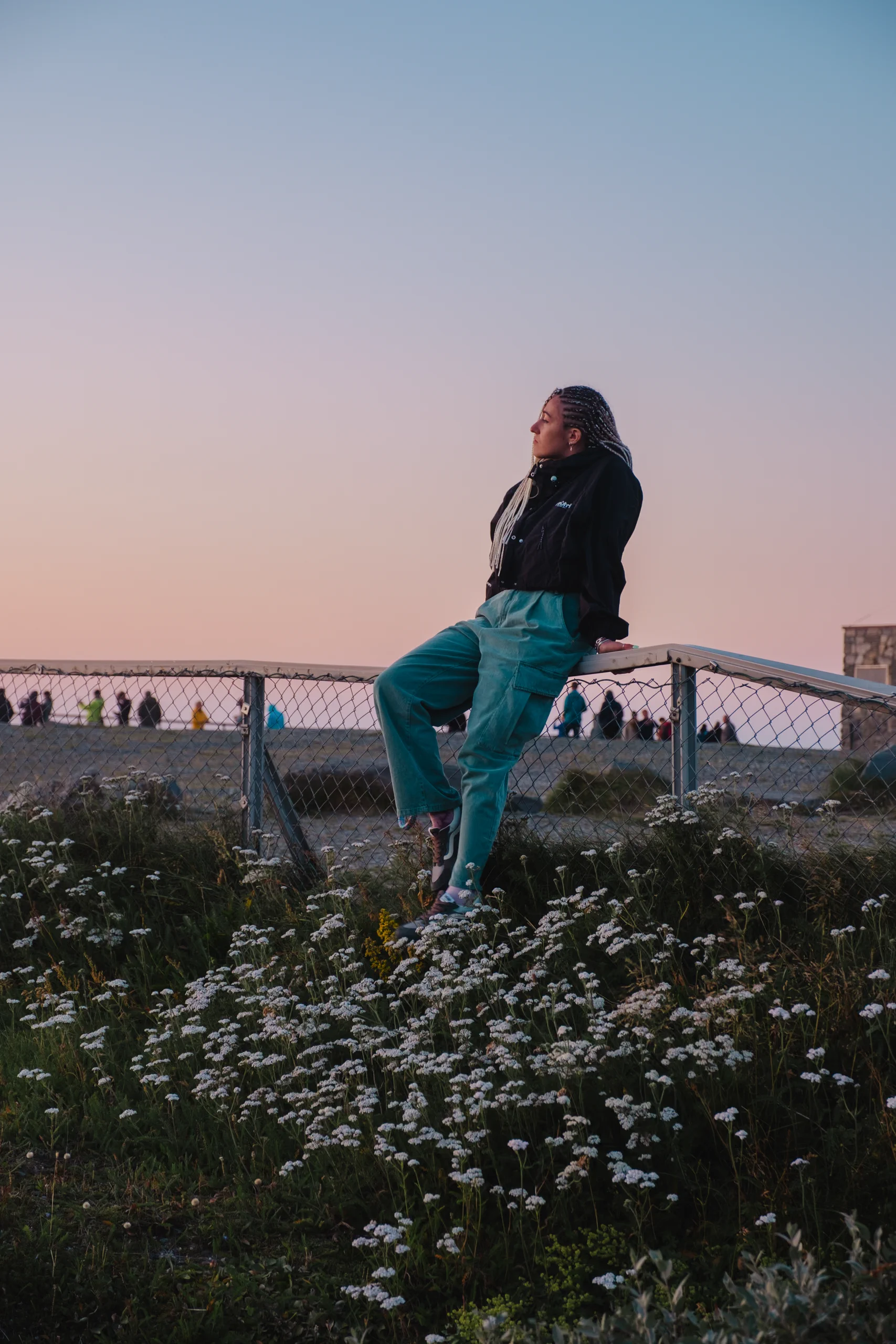 Letizia sitting on a wooden fence overlooking the dramatic cliffs of North Cape.