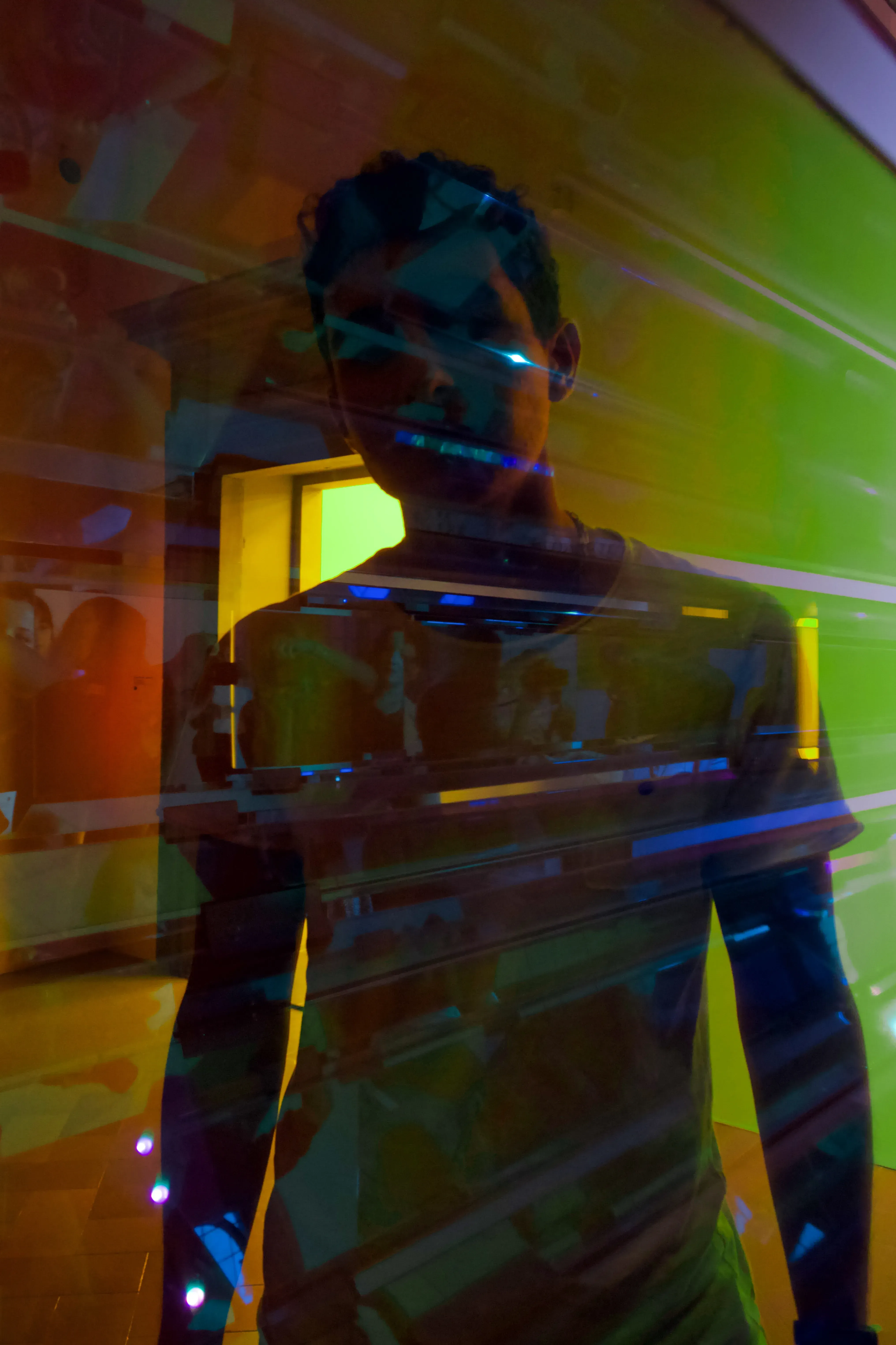 Paolo standing with distorted or multicoloured light reflections cast onto him and the environment.