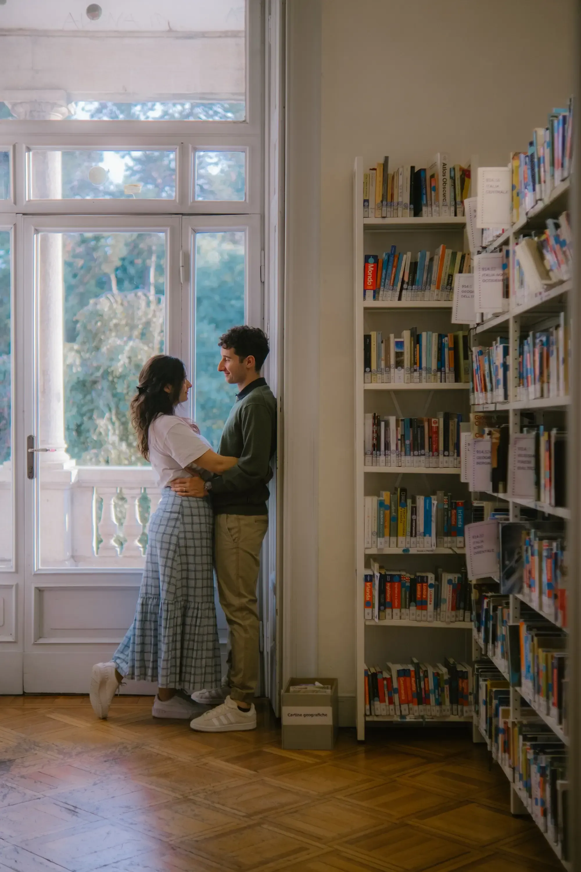 Paolo and Paulina embracing tenderly in a quiet corner of the library.