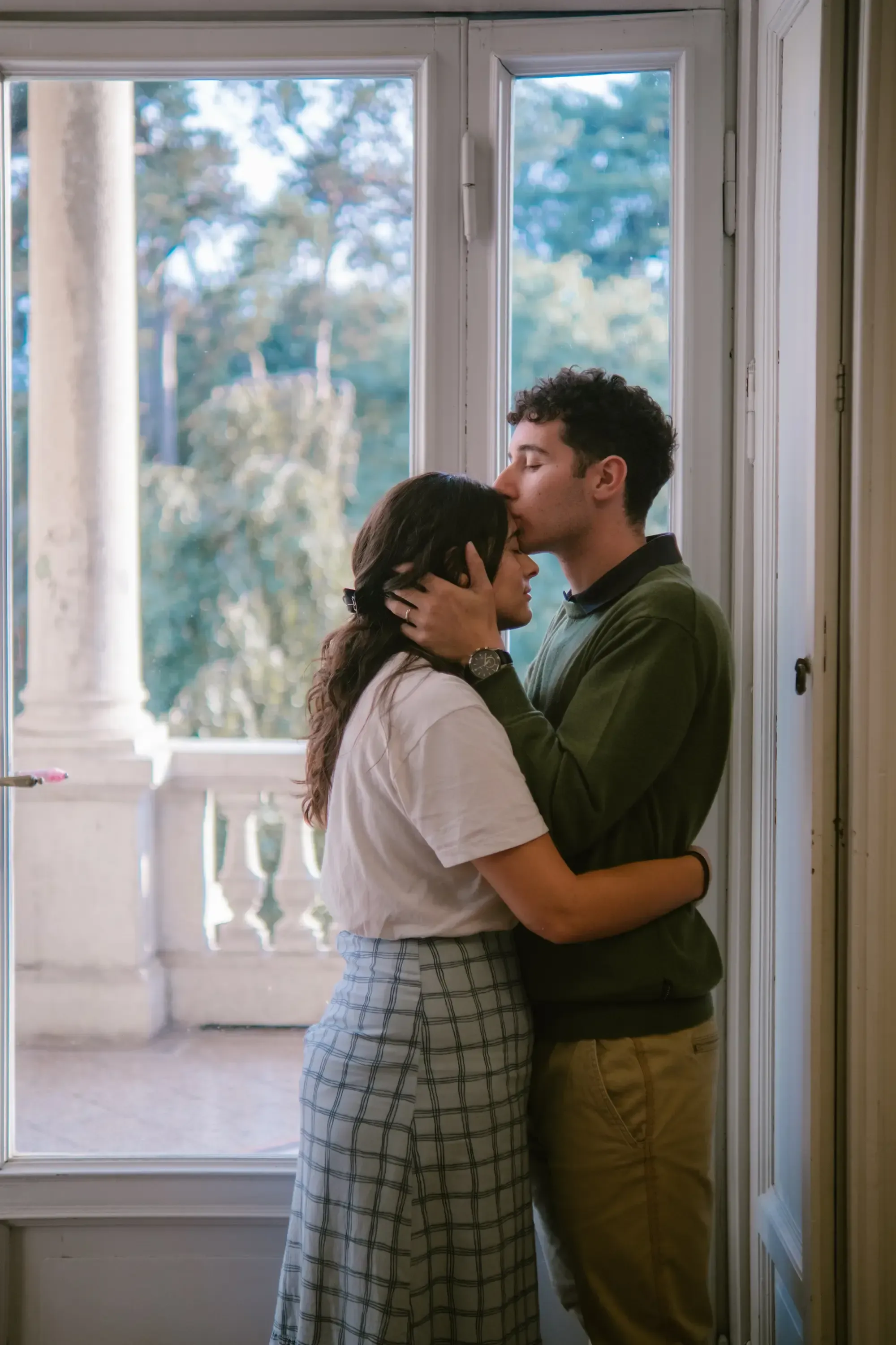 Paolo kissing Paulina with the light from a large library window visible in the background.