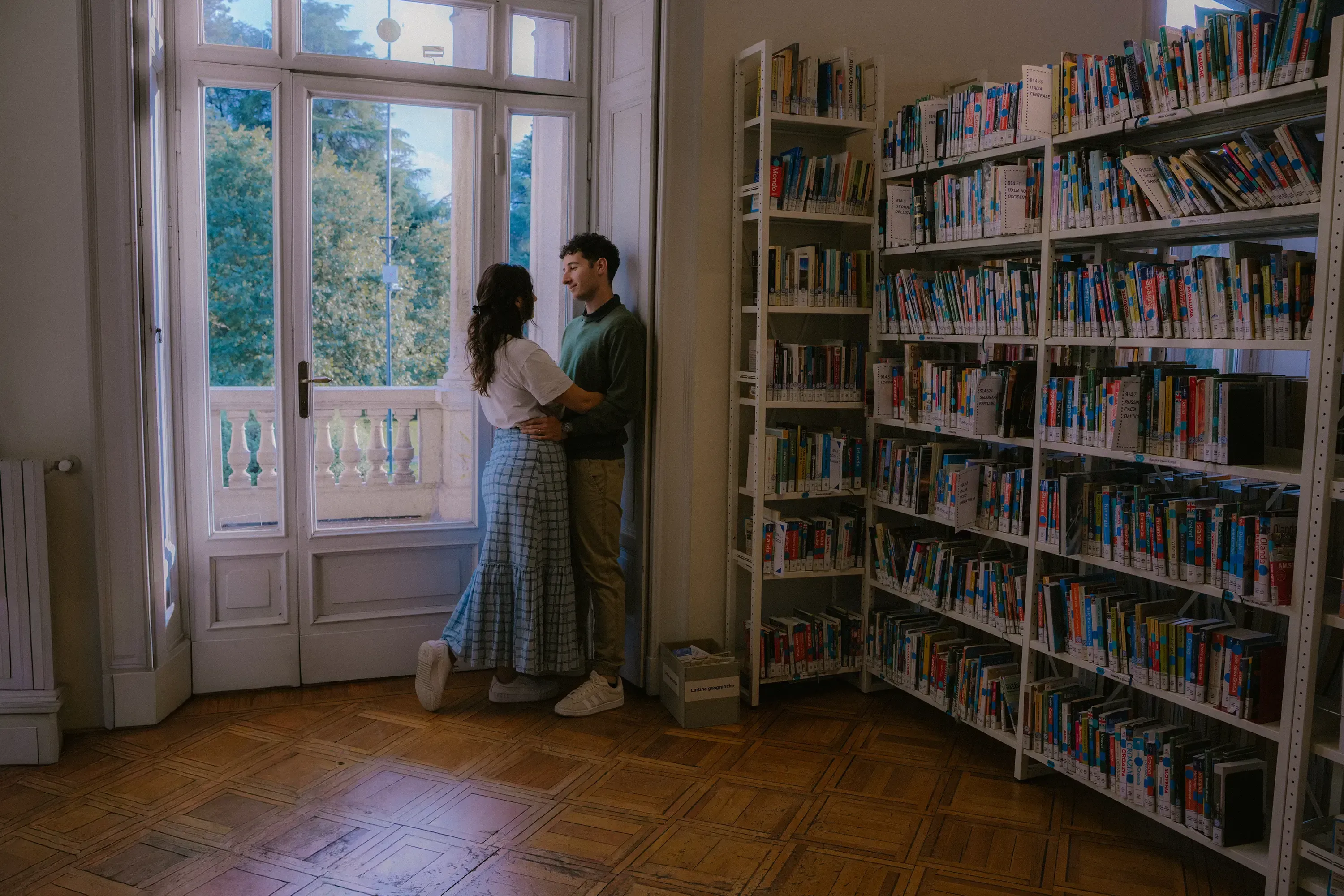Paolo and Paulina embracing tenderly in a quiet corner of the library.