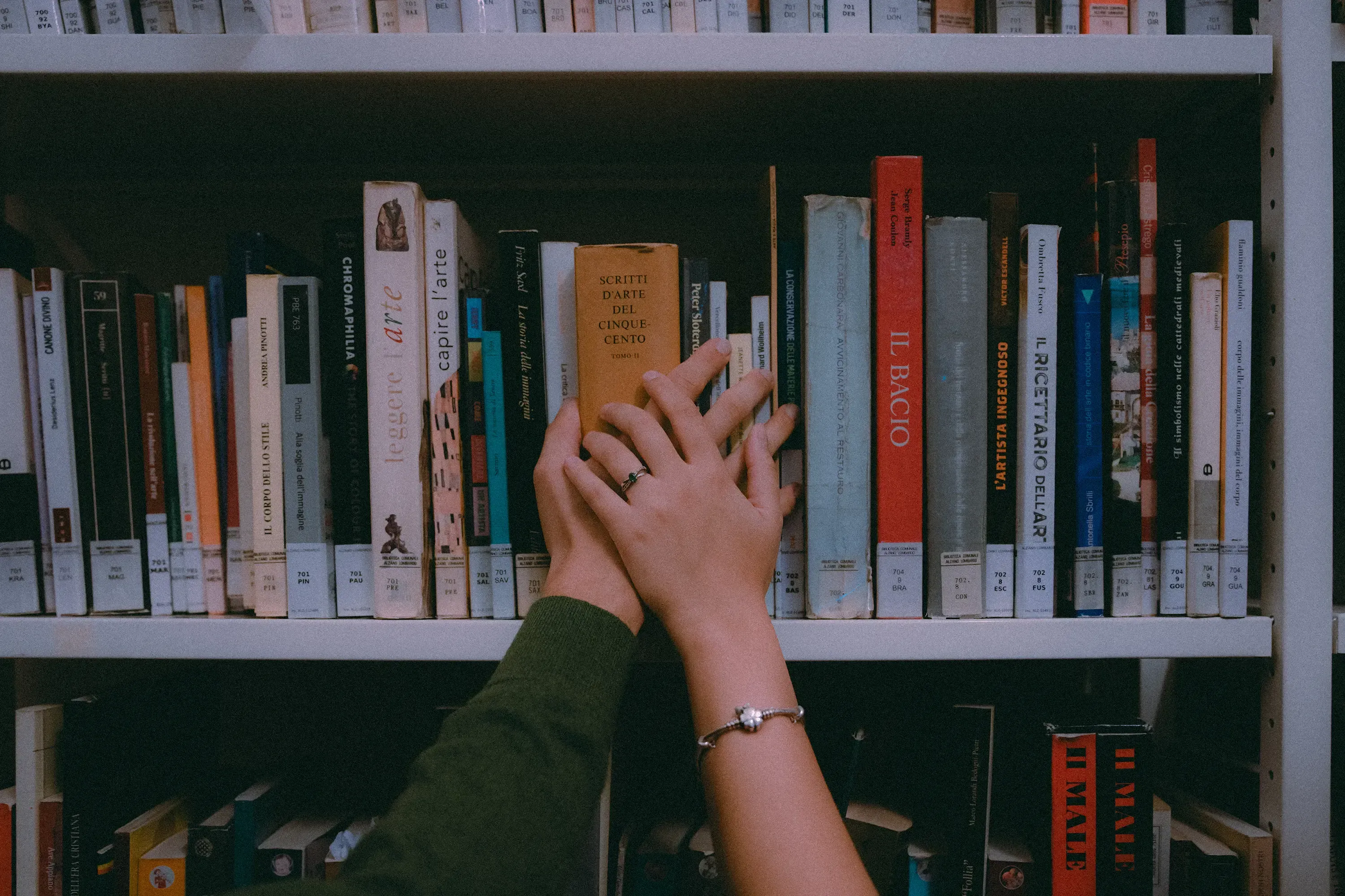 Close-up of Paolo and Paulina's hands linked over an open book in the library.