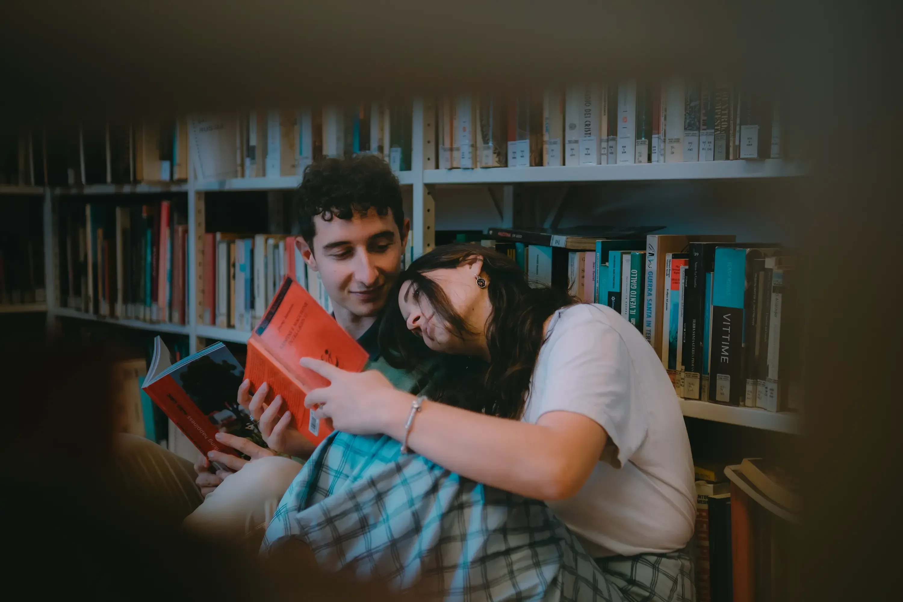 Paulina leaning against Paolo as they sit and read books together.