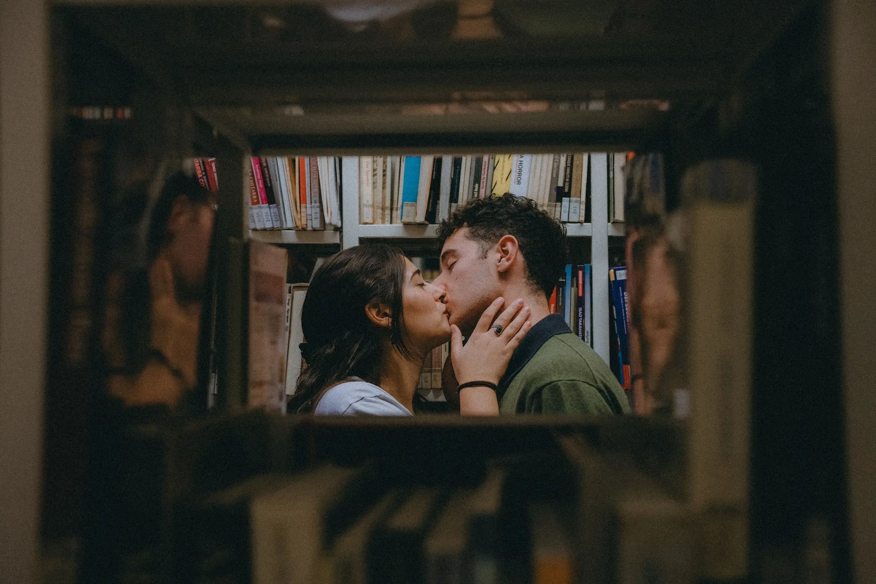 Paolo and Paulina kissing, closely framed by the surrounding books on the shelves.