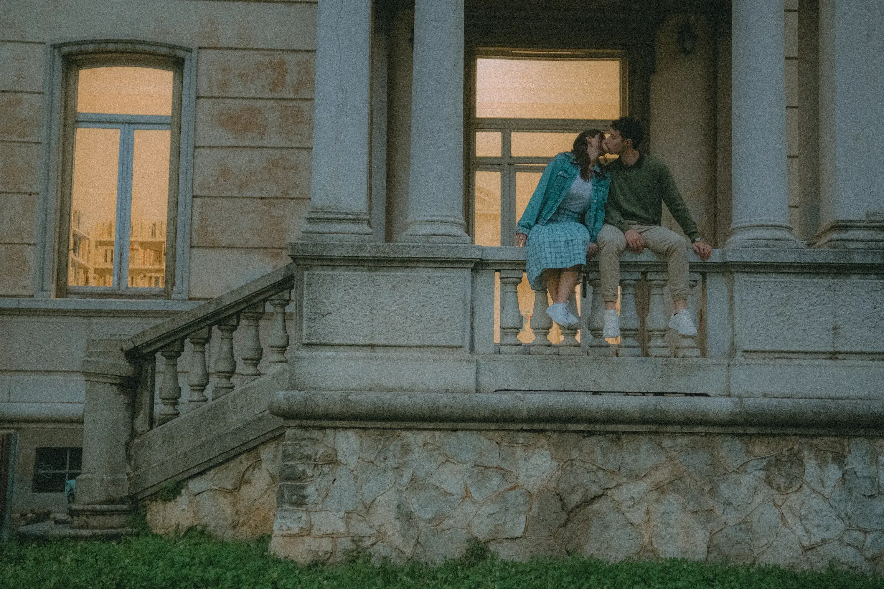 Paolo and Paulina kissing outside the library while sitting down.