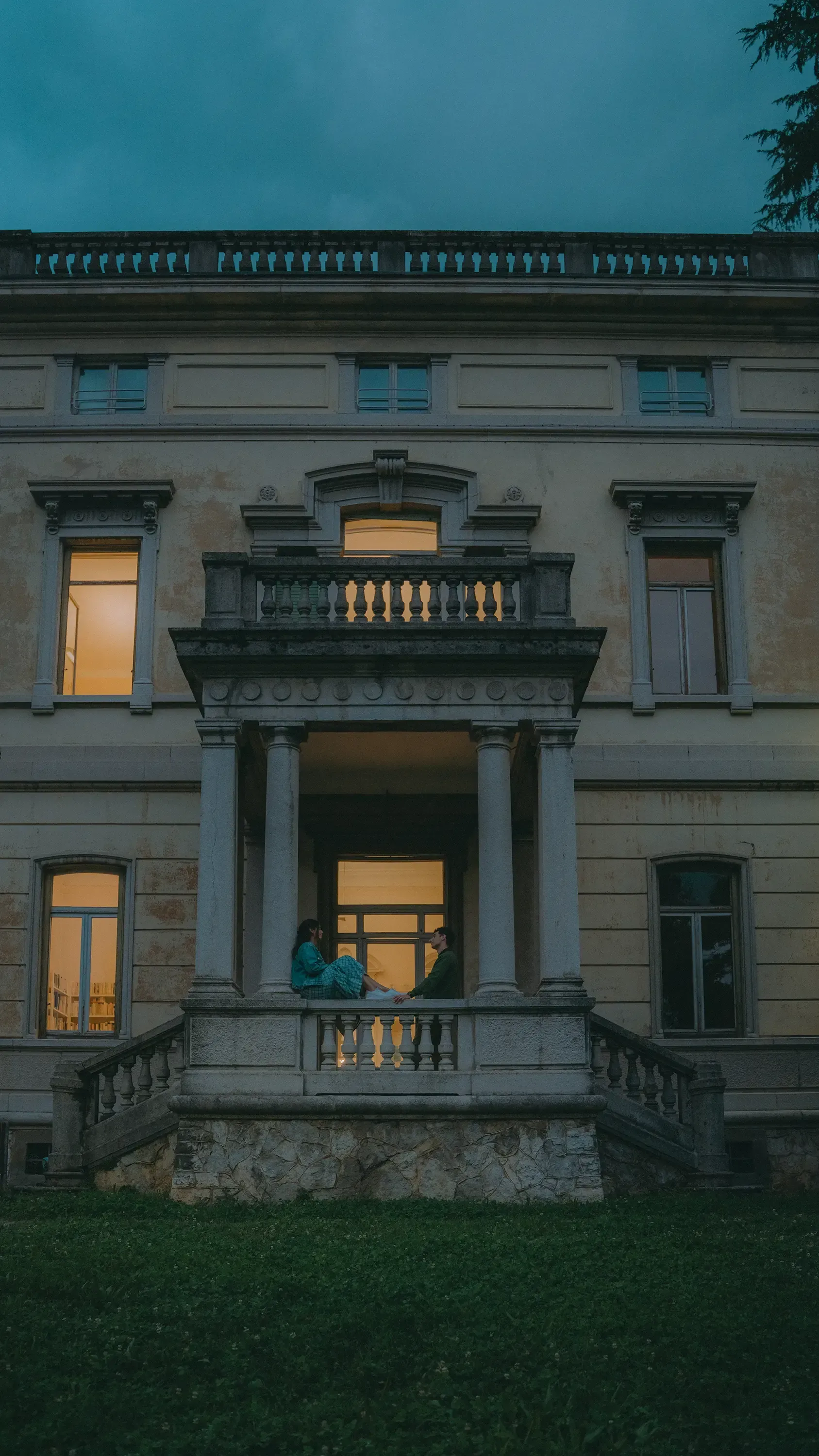 Wide shot of Paolo and Paulina kissing while seated on the low wall.