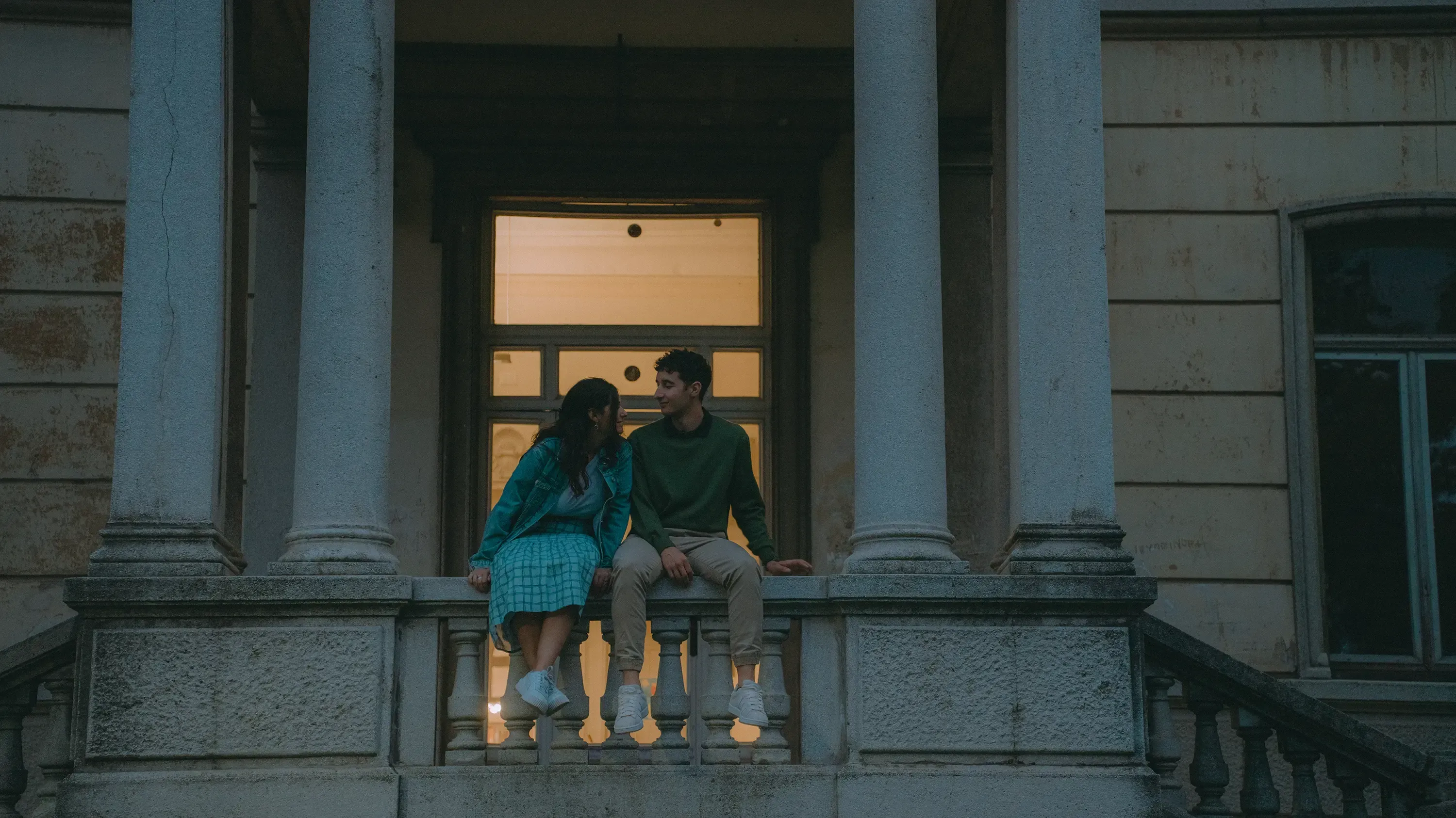 Paolo and Paulina sitting next to each other on a low wall outside the library.