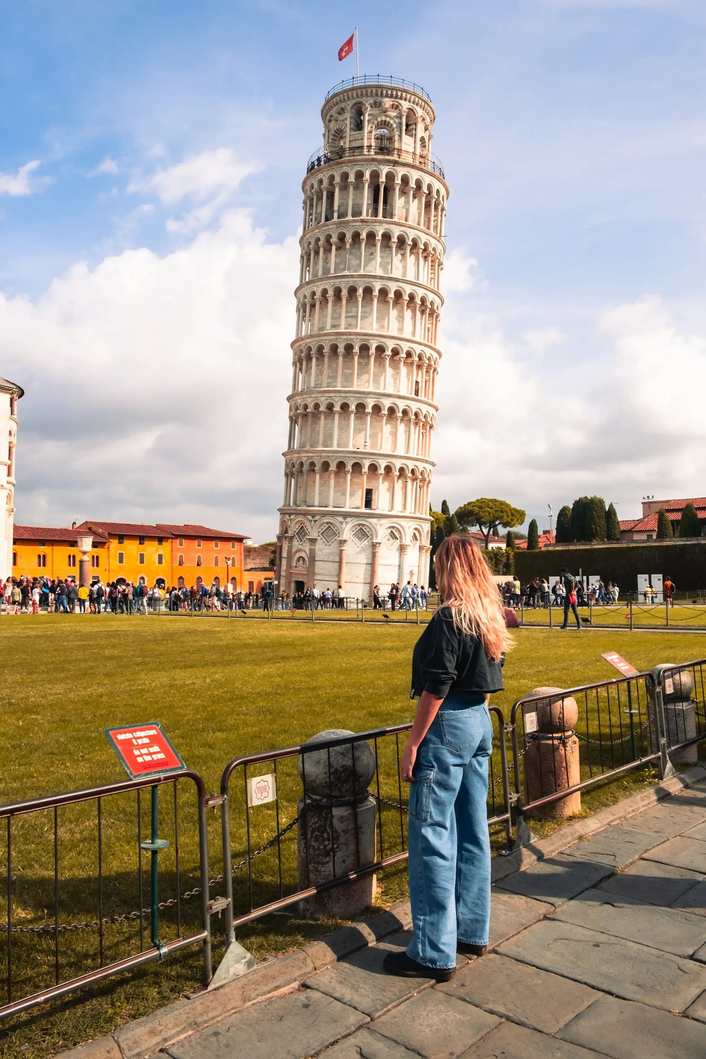 Letizia looking up and observing the dramatic tilt of the Leaning Tower of Pisa.