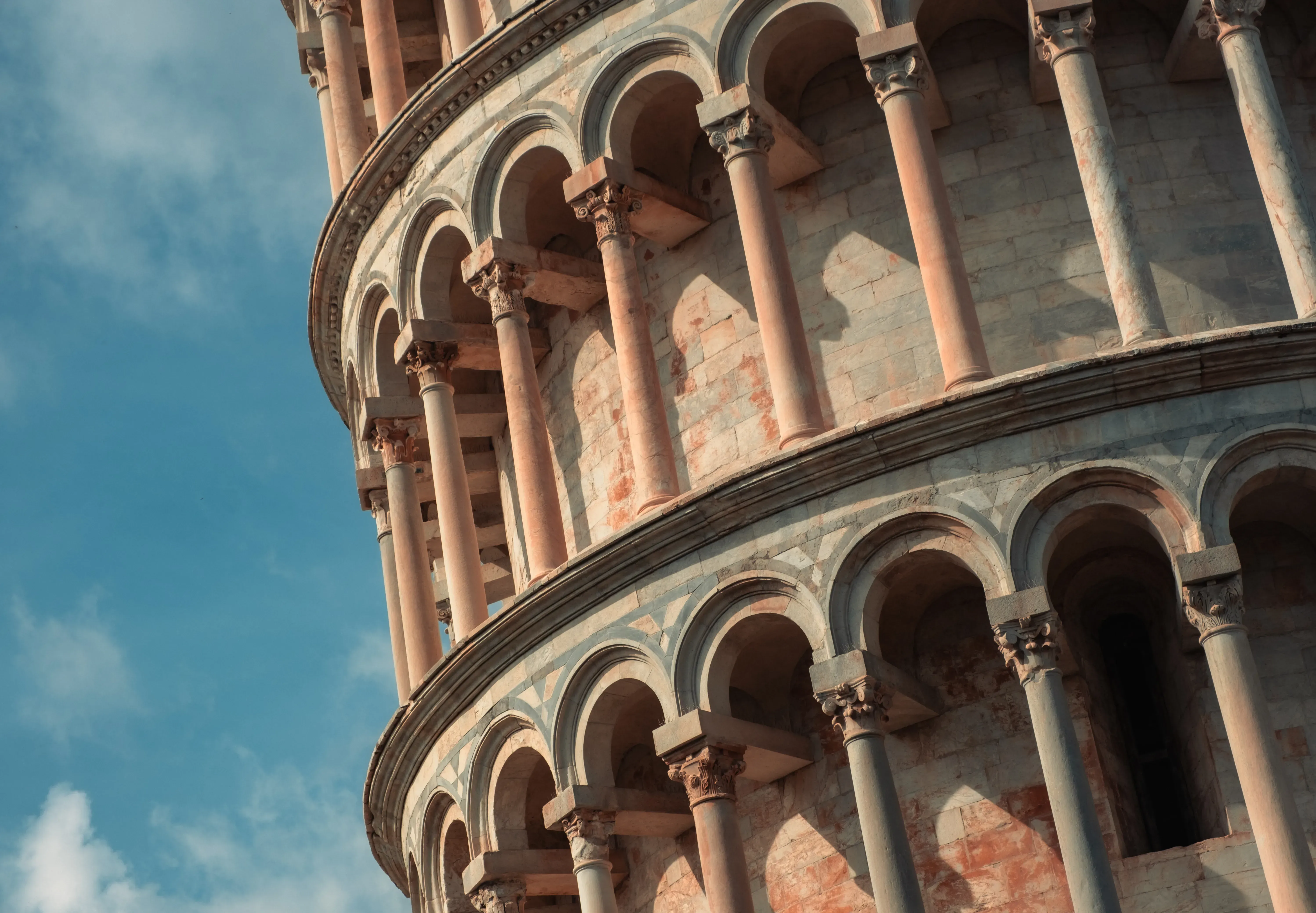 Close-up view of the white marble columns and architectural details of the Leaning Tower of Pisa.