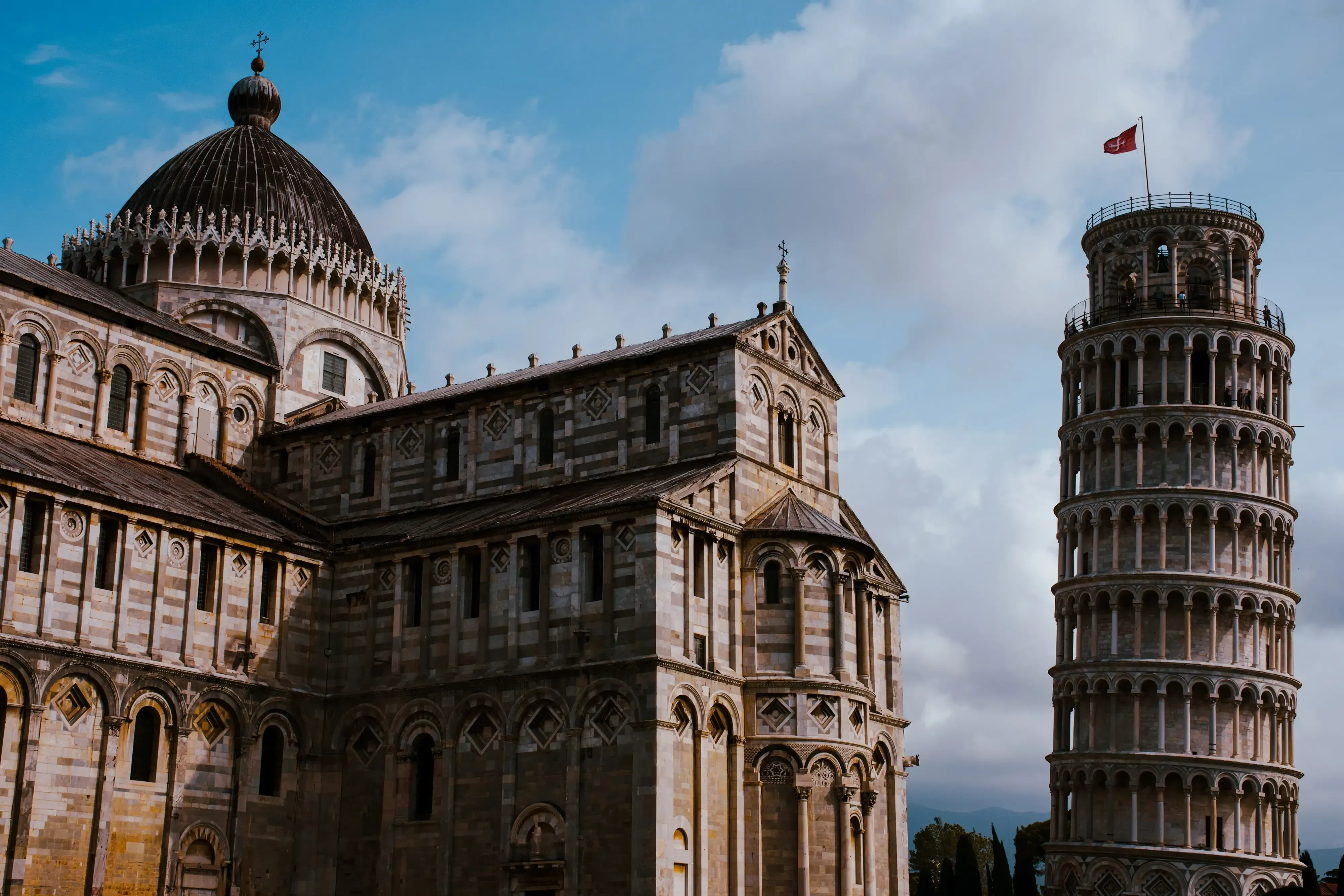 The Leaning Tower of Pisa and the large marble Cathedral (Duomo) standing side-by-side.