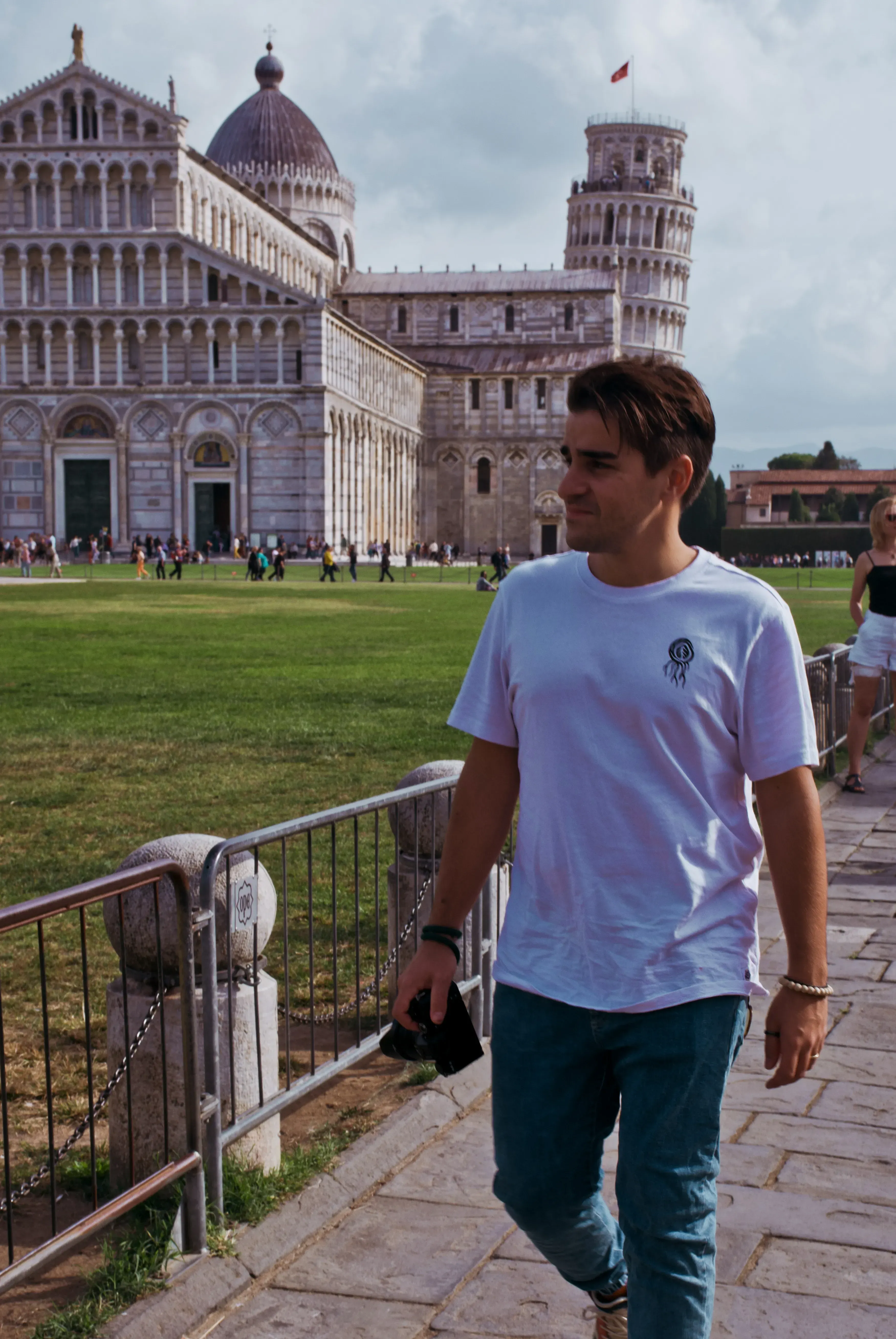 Ieser walking across the green lawn of the square in Pisa.