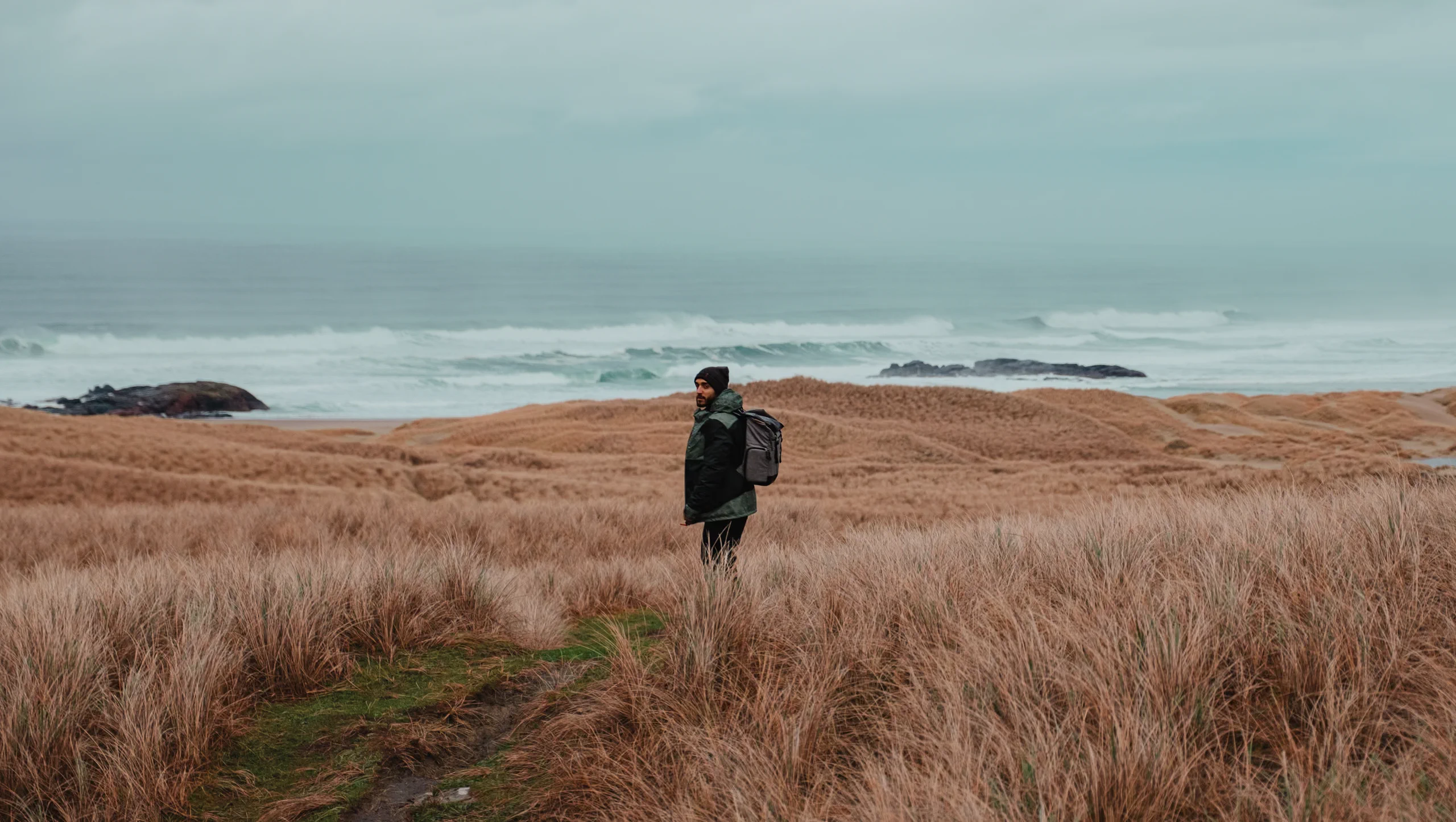 Stefano standing waist-deep in tall Scottish grass with the sea in the background.