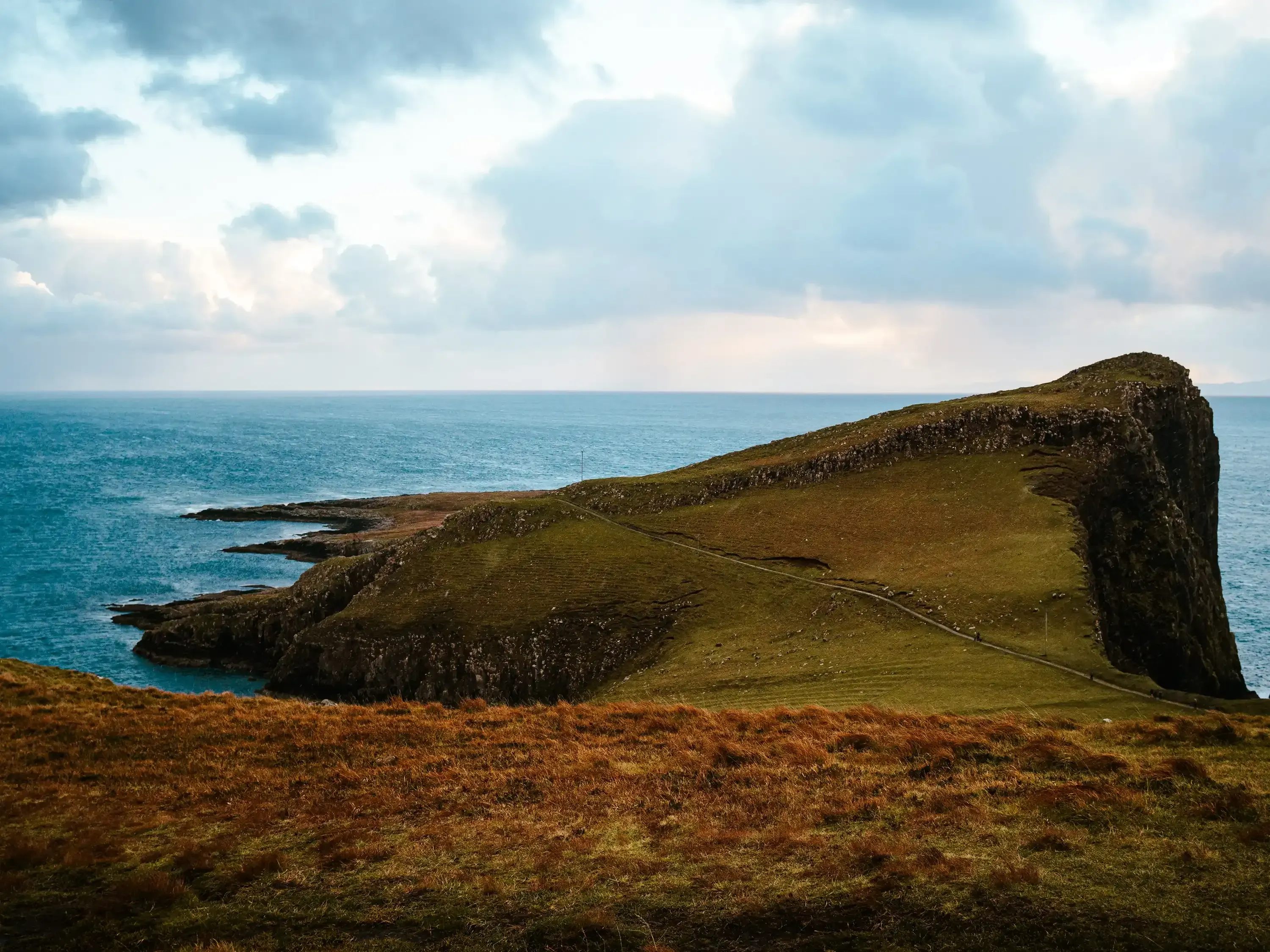 The sloping, grassy cliffside leading out towards the Neist Point Lighthouse.