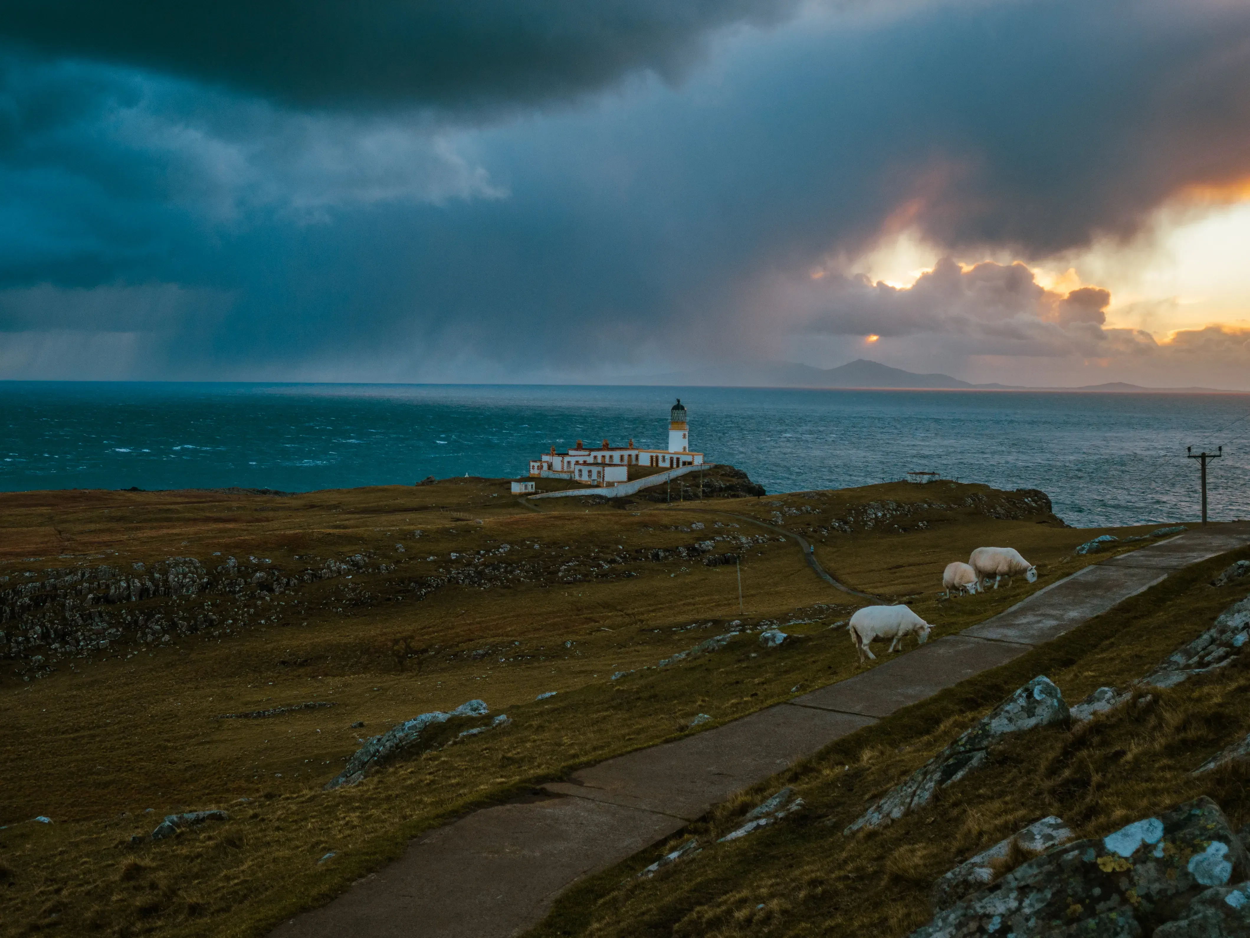 The Neist Point Lighthouse, a white structure standing on the far edge of the peninsula.