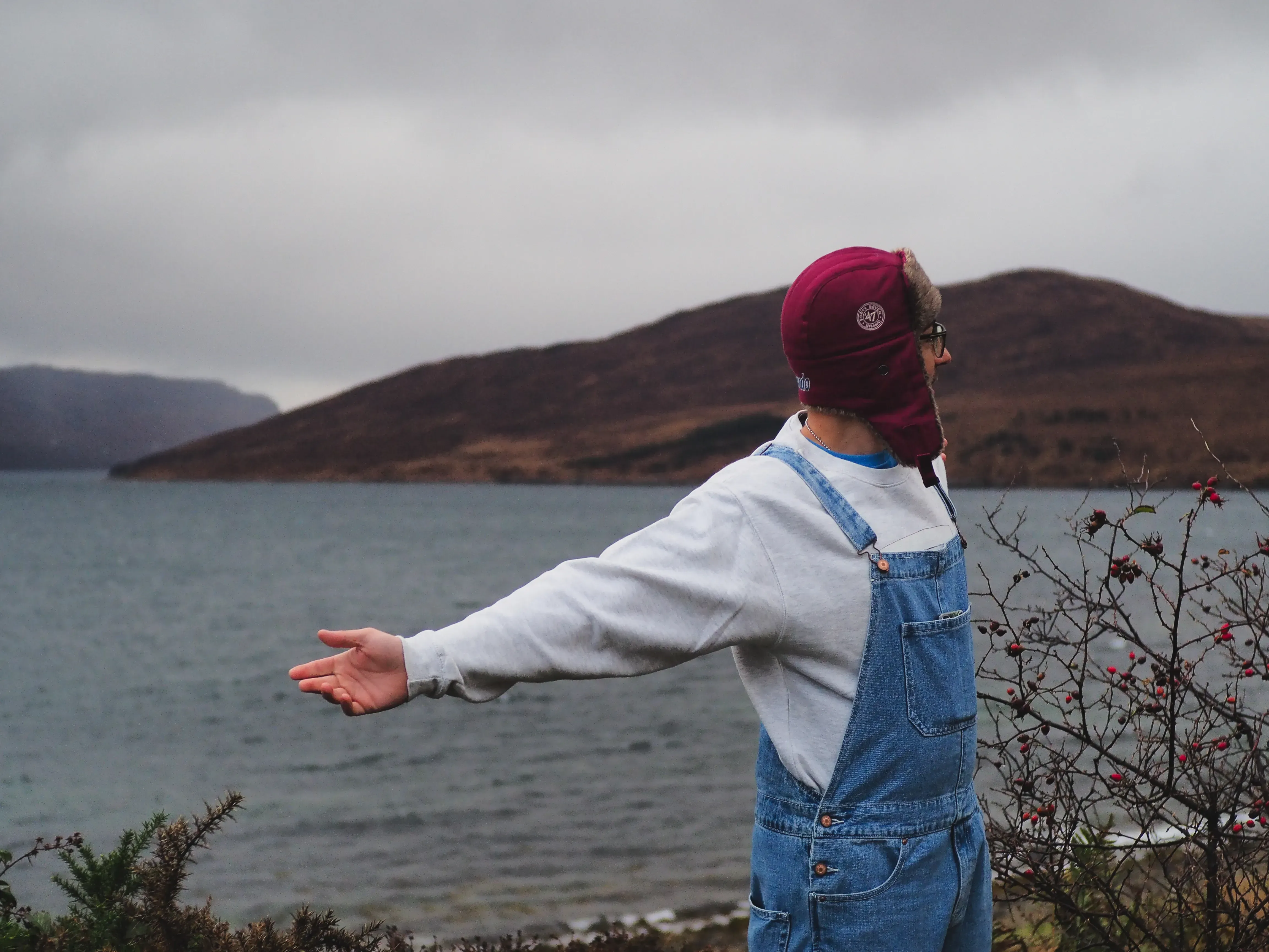 Iair standing on the cliff edge, spreading his arms wide towards the expansive ocean.